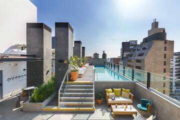 a rooftop pool with chairs and a table