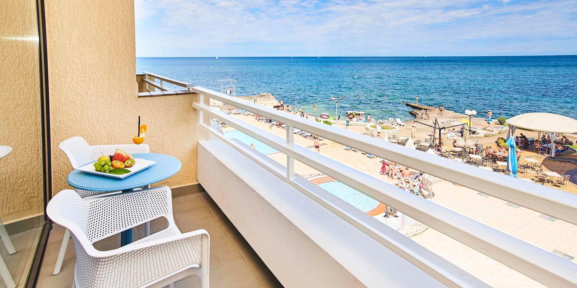 a balcony with a table and chairs and a beach in the background