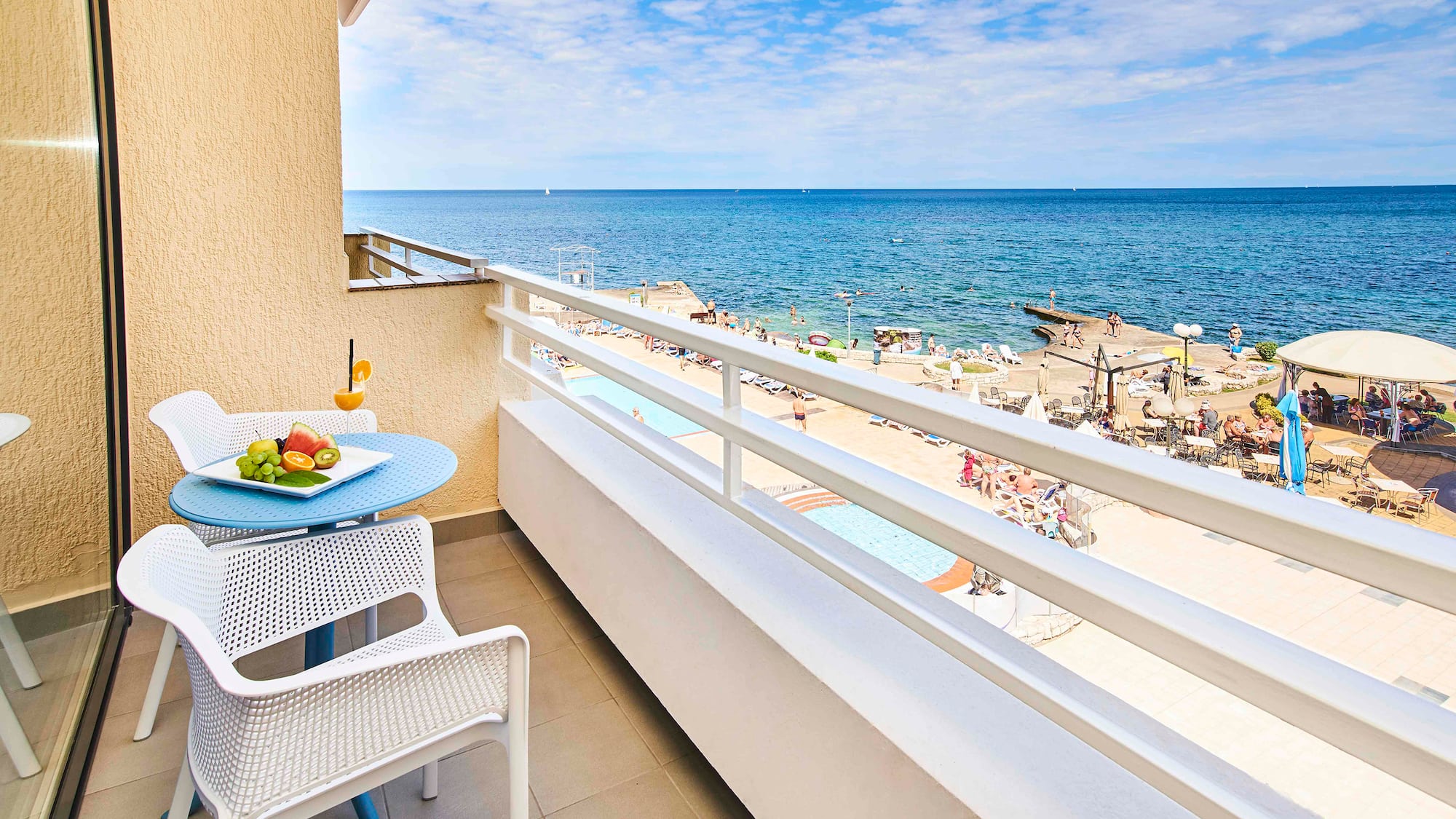 a balcony with a table and chairs and a beach in the background
