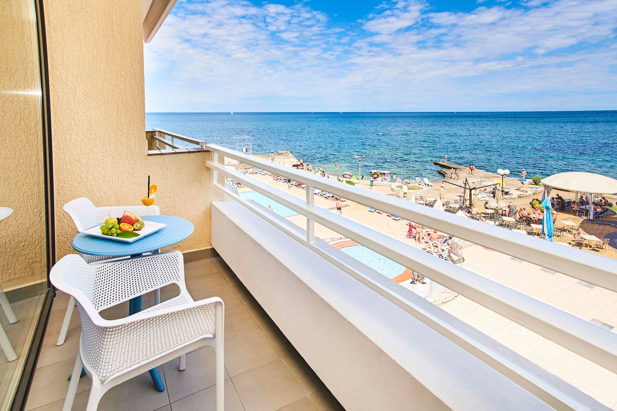 a balcony with a table and chairs and a beach in the background