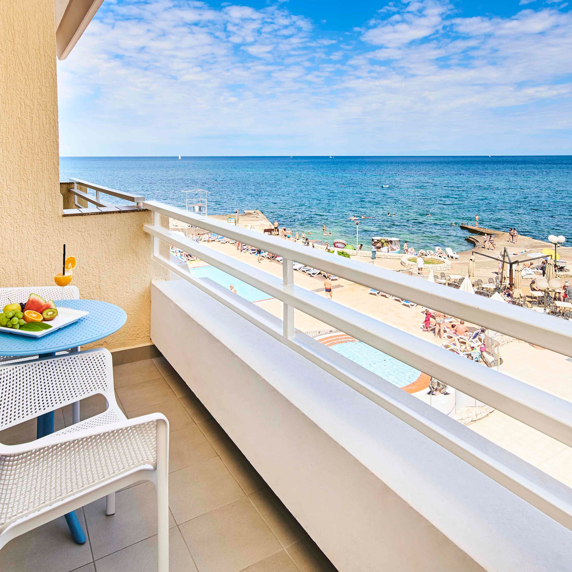 a balcony with a table and chairs and a beach in the background