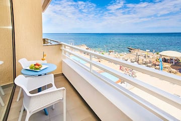 a balcony with a table and chairs and a beach in the background