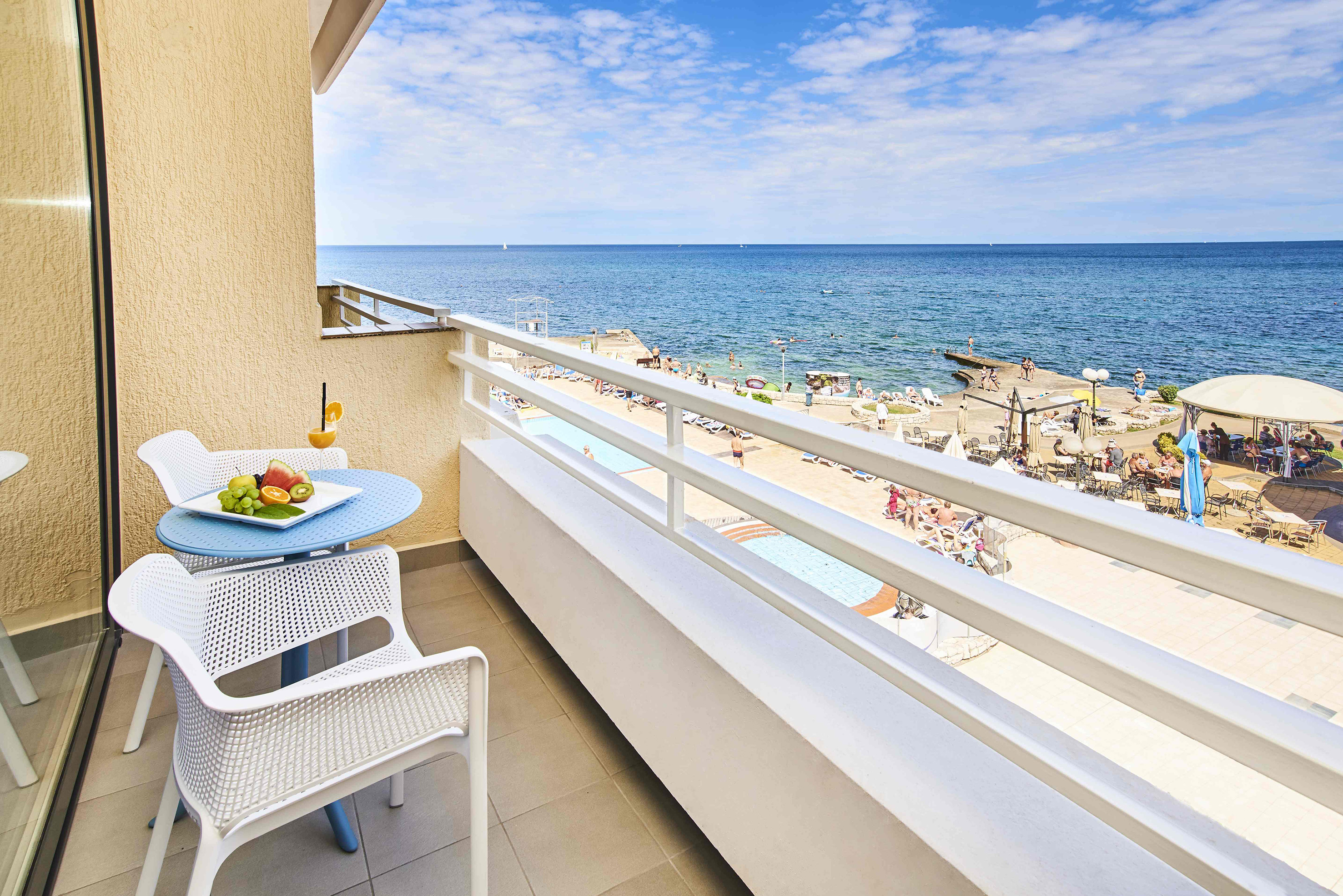 a balcony with a table and chairs and a beach in the background