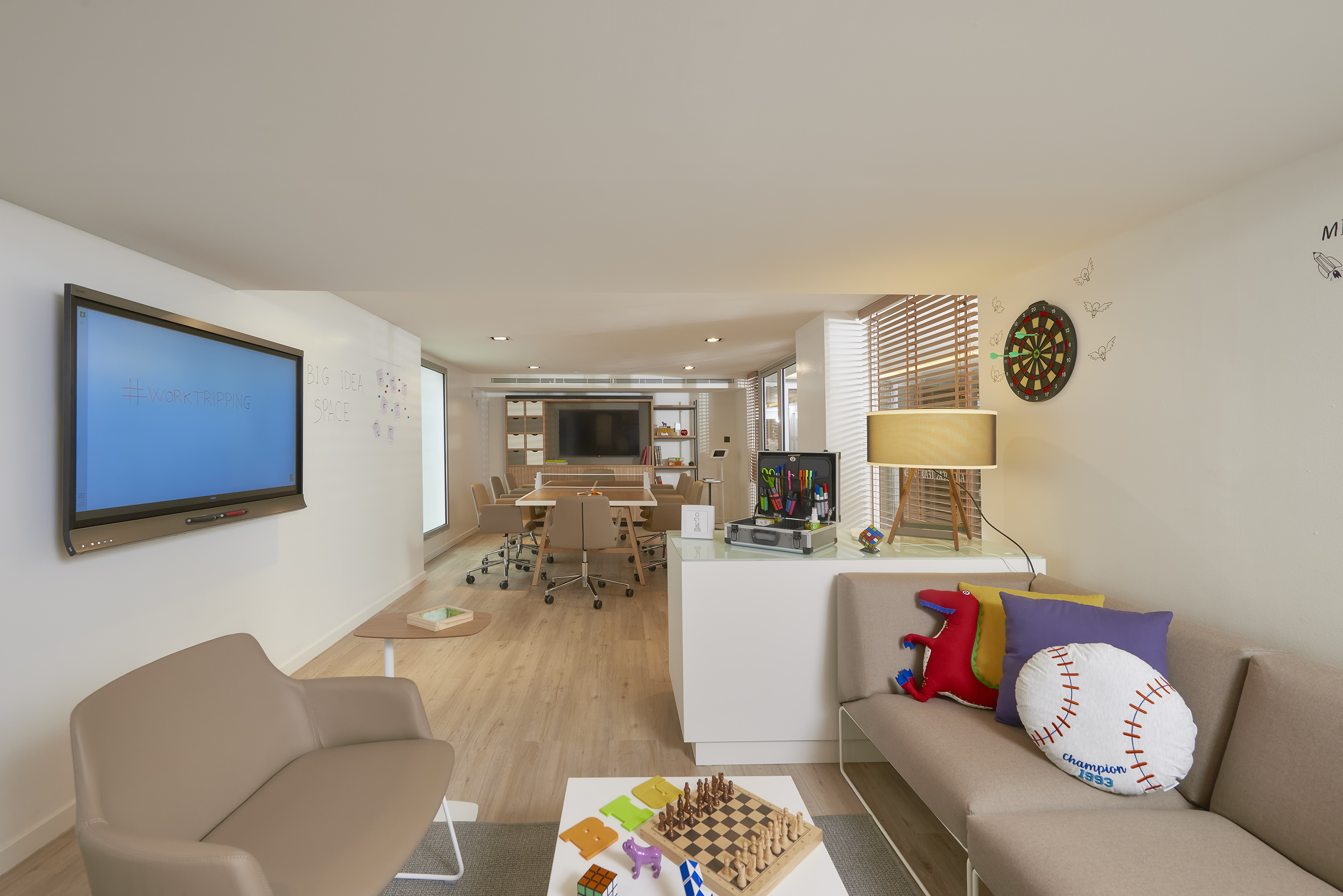 Modern collaborative workspace with interactive screen and creative lounge.