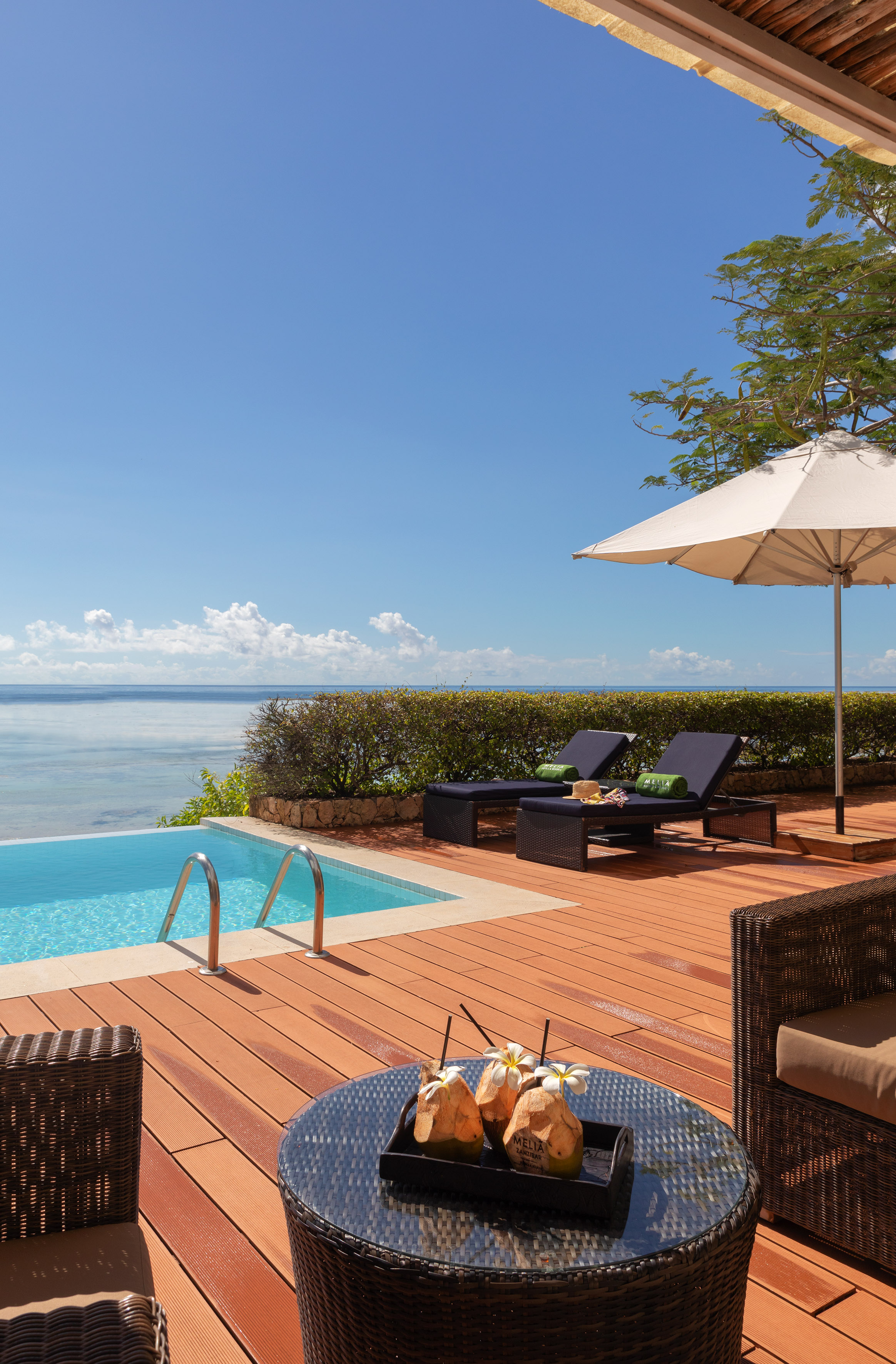 Oceanfront private pool deck with lounge chairs and tropical coconut drinks.