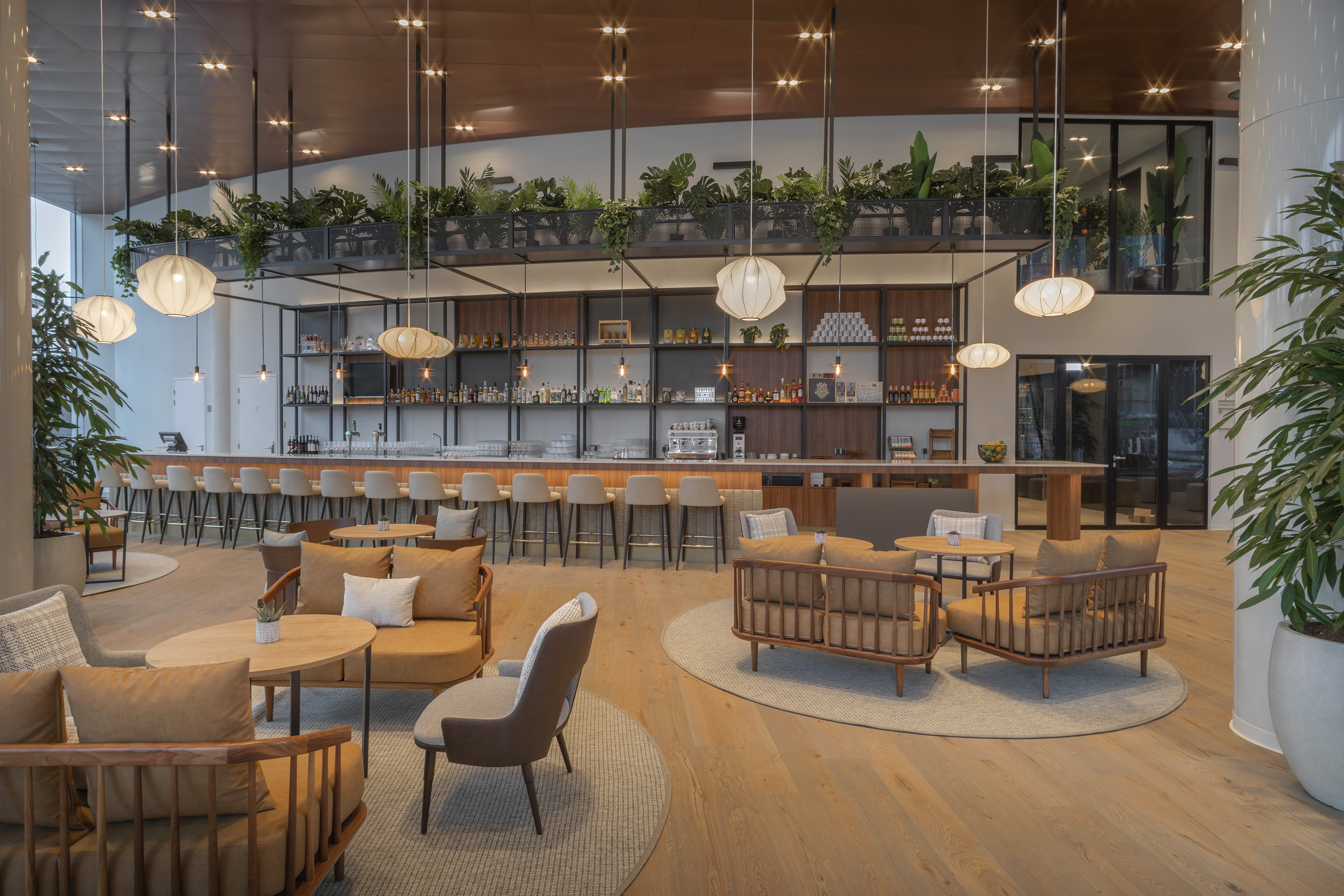 Contemporary bar and lounge, long counter, lush plants, and stylish seating areas.