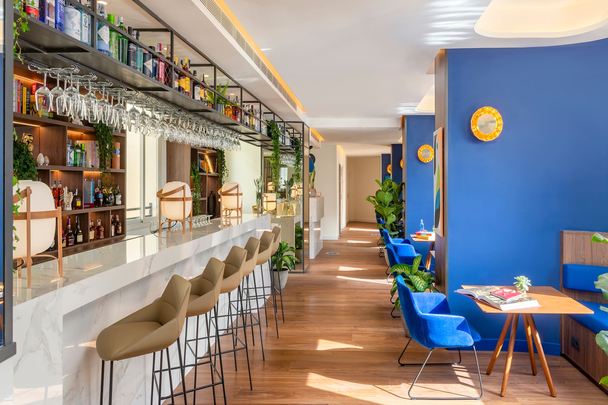 Stylish modern hotel bar with marble counter, liquor display, and blue lounge seating.