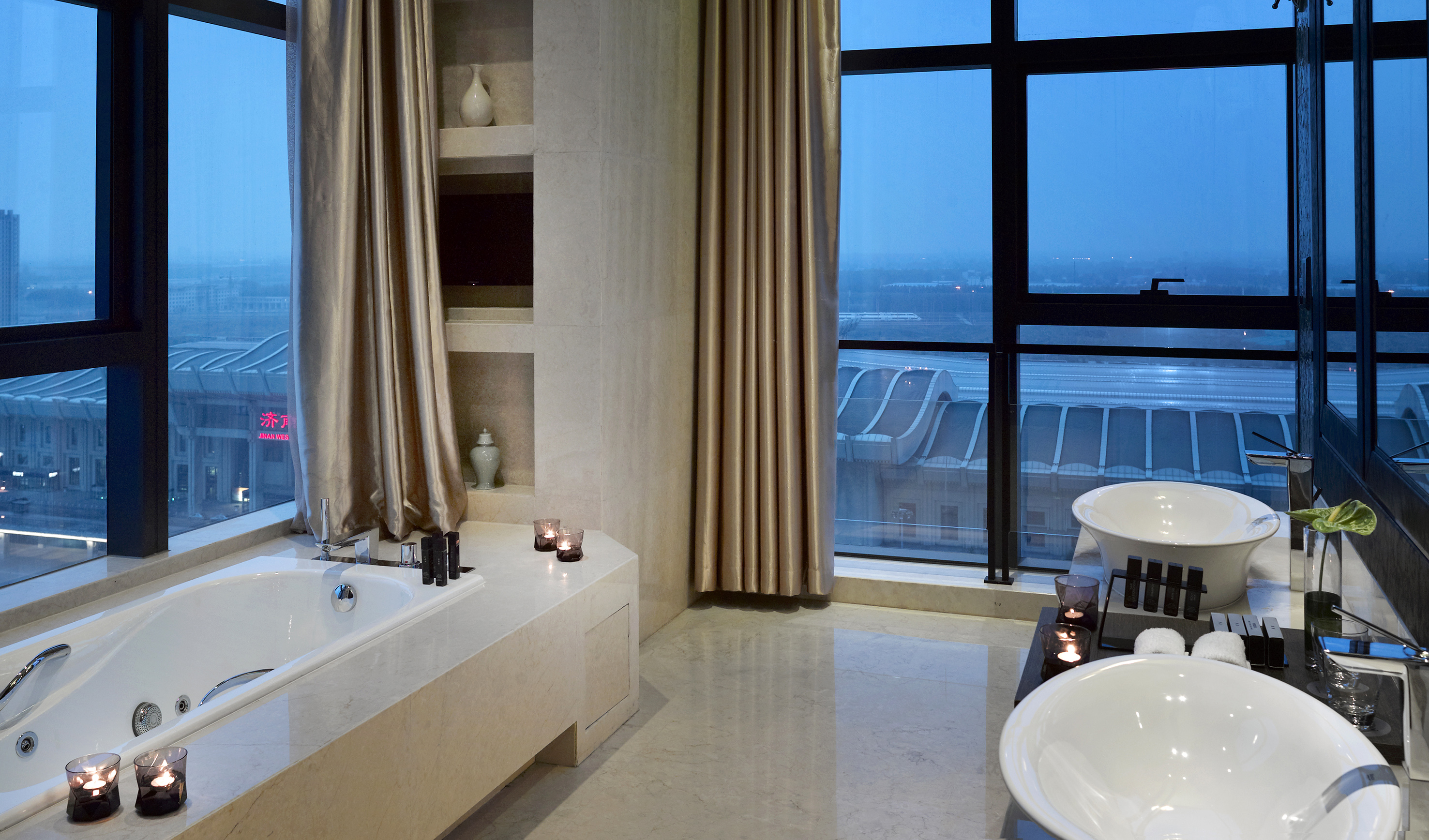 Modern luxury bathroom with panoramic city view, bathtub, and dual sinks.