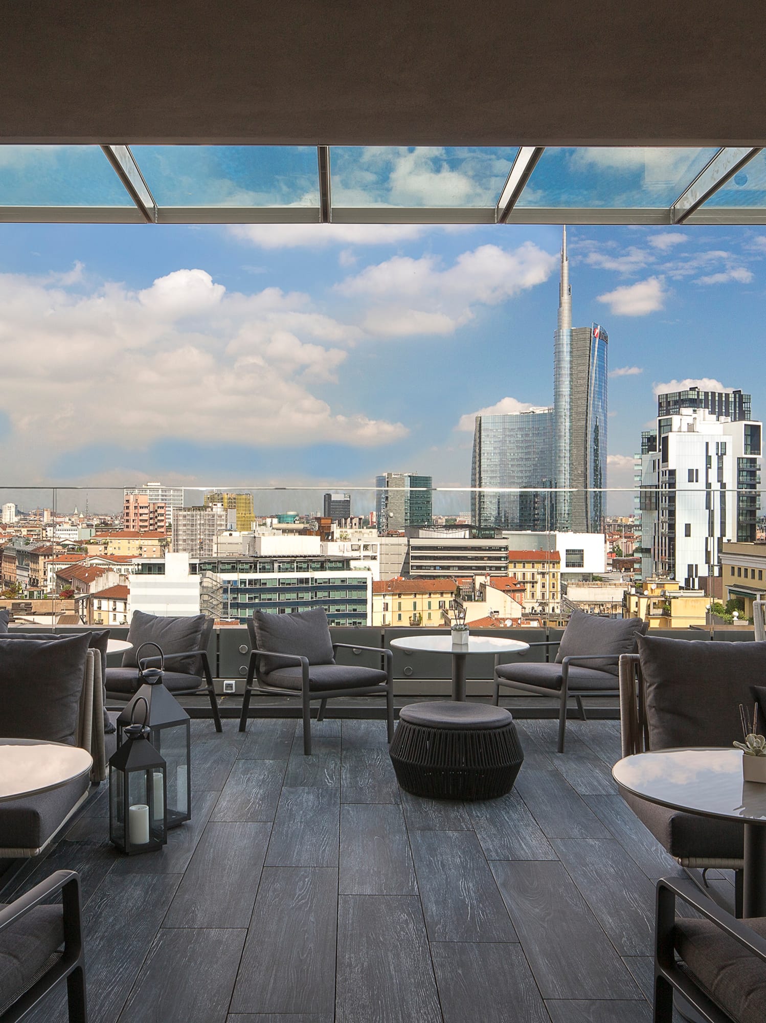 a rooftop patio with tables and chairs and a city view