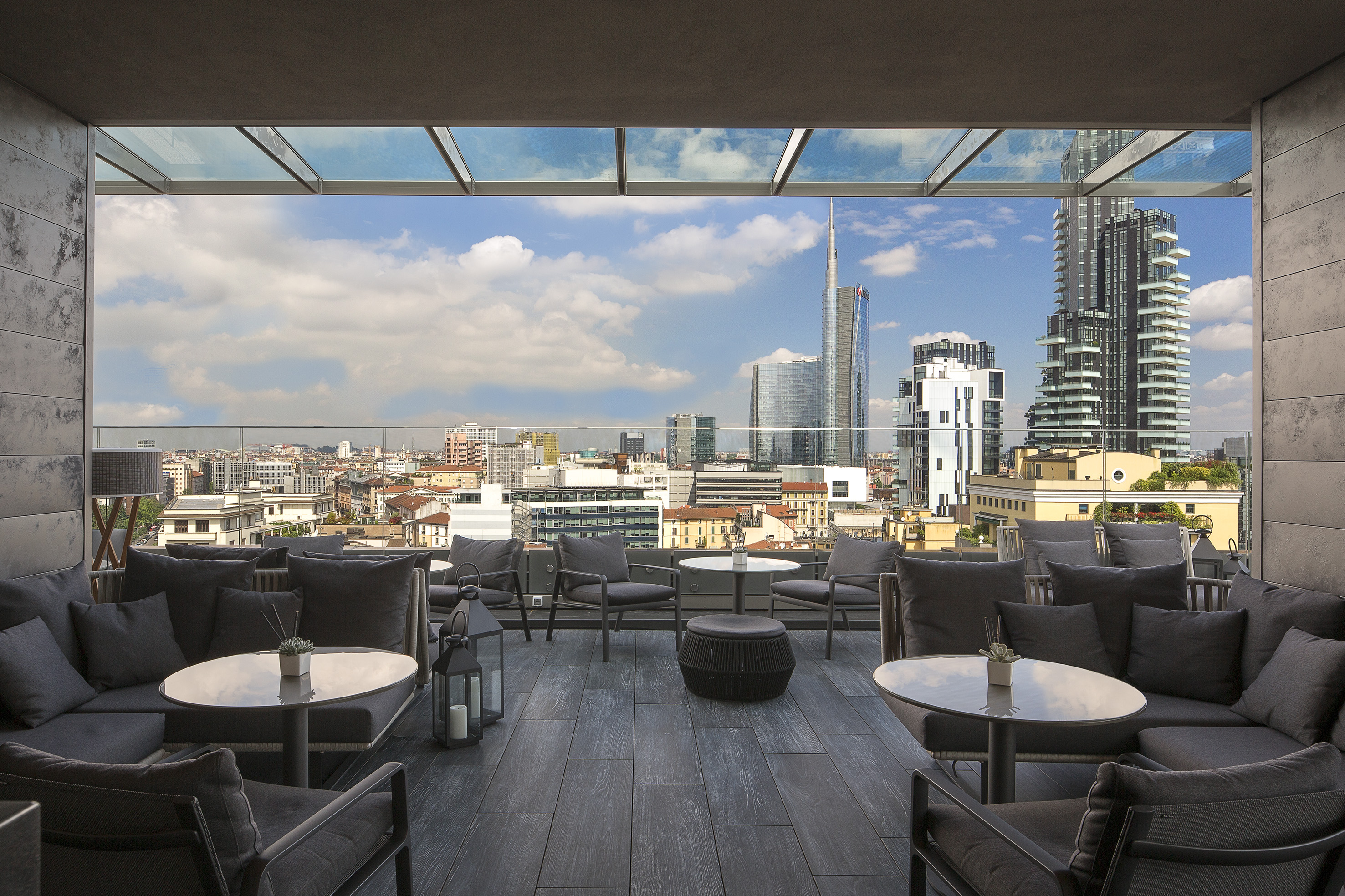 a rooftop patio with tables and chairs and a city view