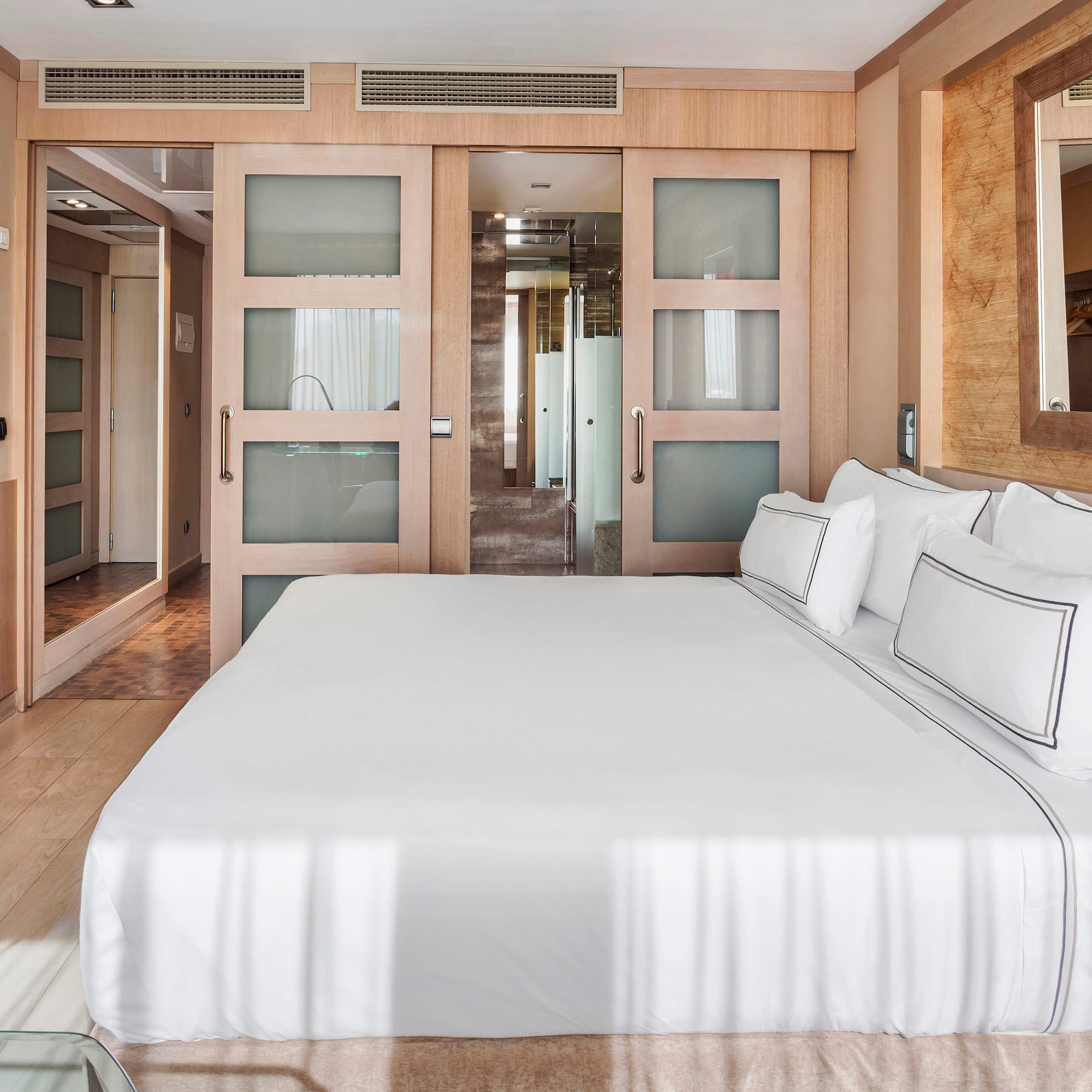 a bed with white sheets and pillows in a room with wood walls