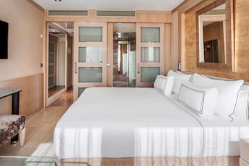 a bed with white sheets and pillows in a room with wood walls