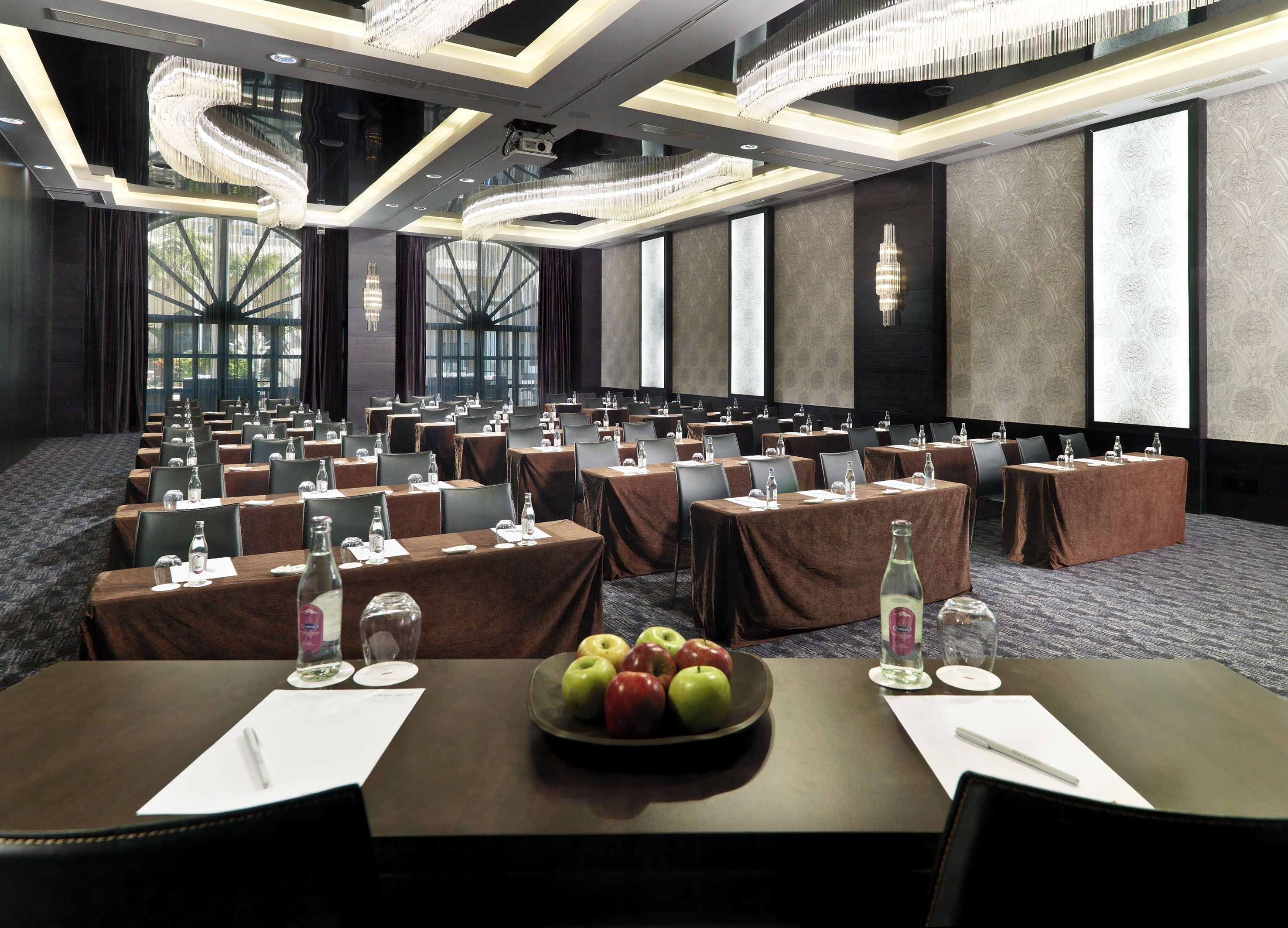 Elegant meeting room setup with tables, chairs, and grand chandeliers.