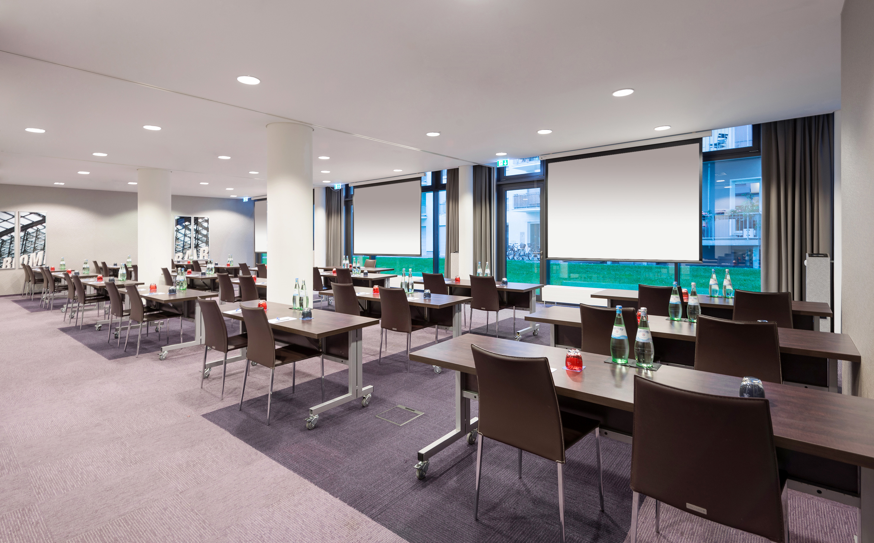 Bright modern conference room with tables, chairs, and projector screens.