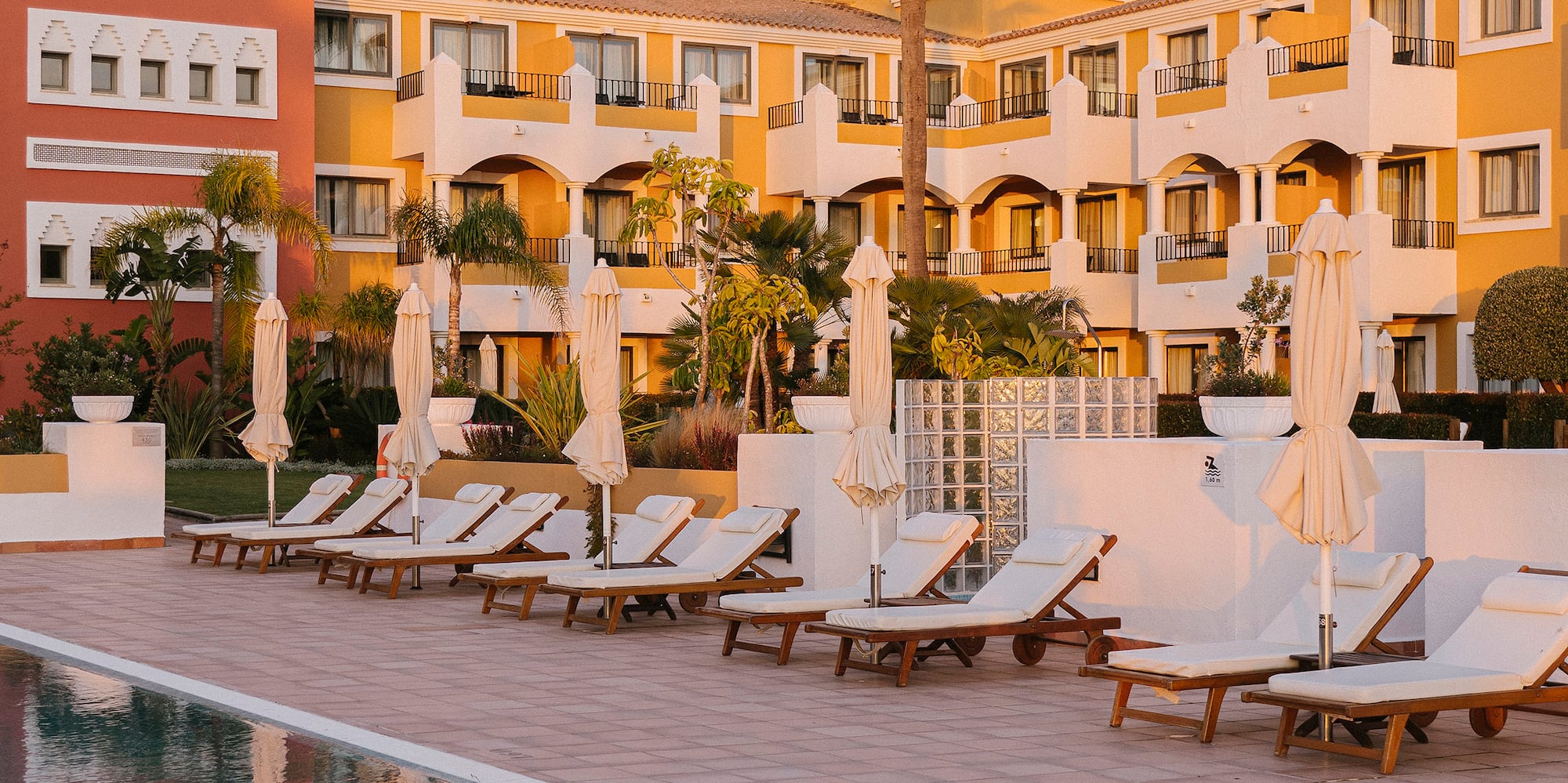 a pool with lounge chairs and umbrellas in front of a building