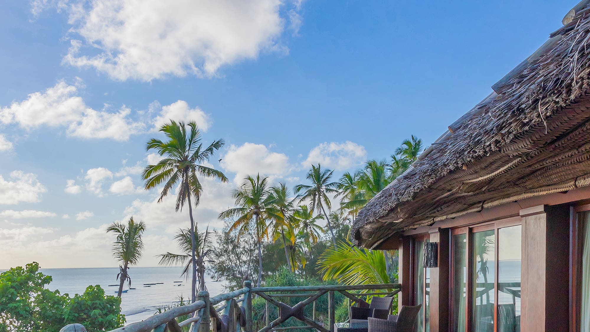 a deck with a thatched roof and a view of the ocean