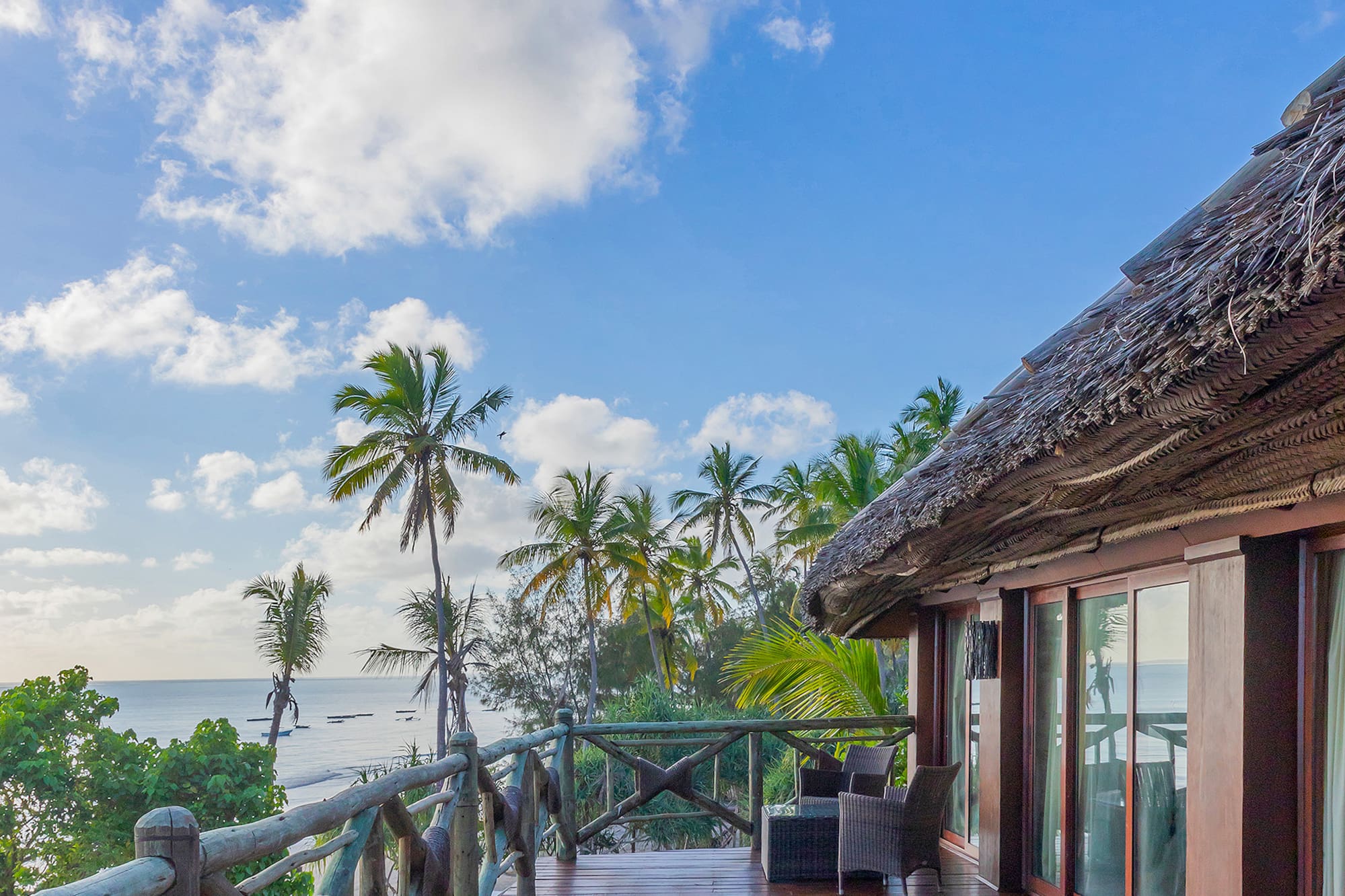 a deck with a thatched roof and a view of the ocean