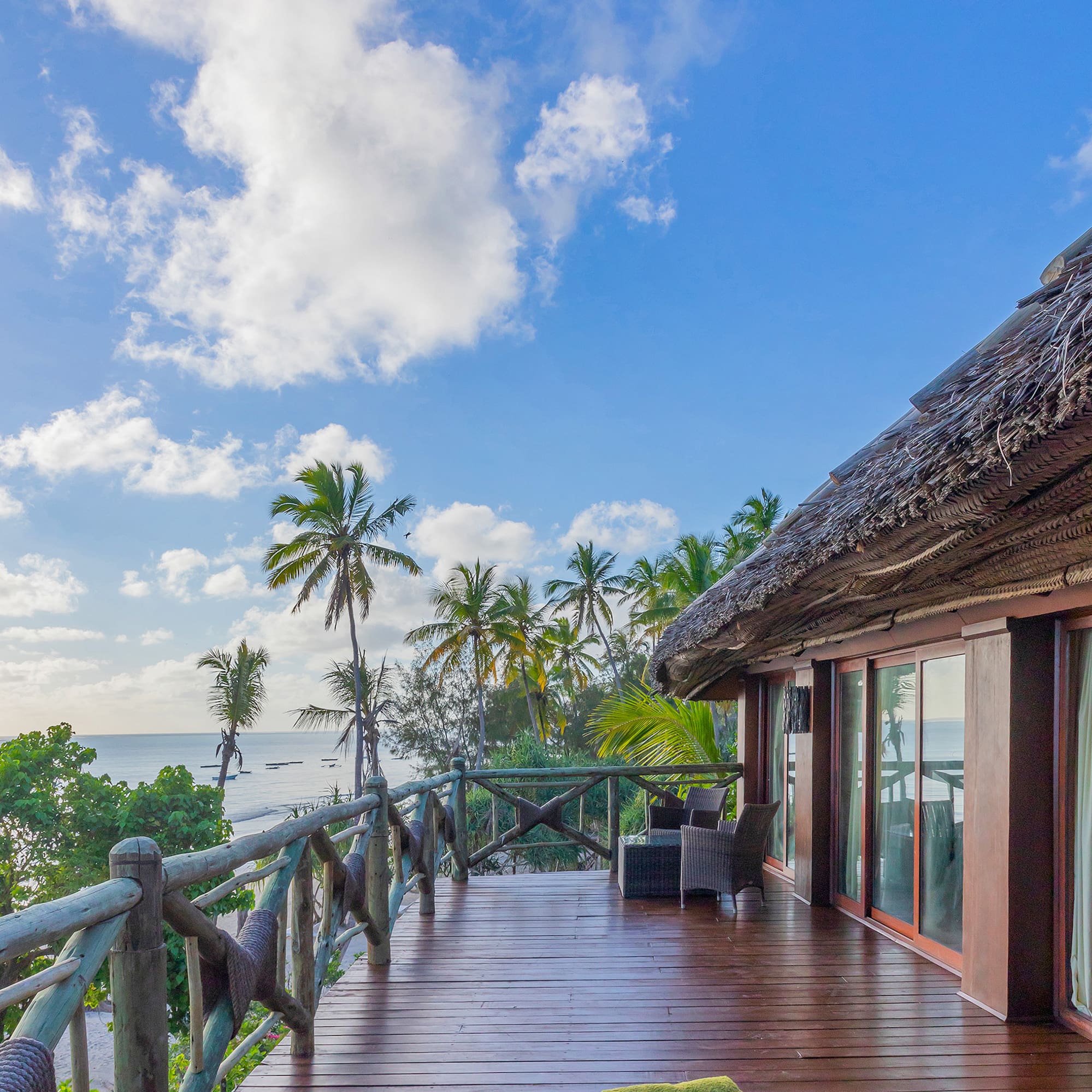 a deck with a thatched roof and a view of the ocean