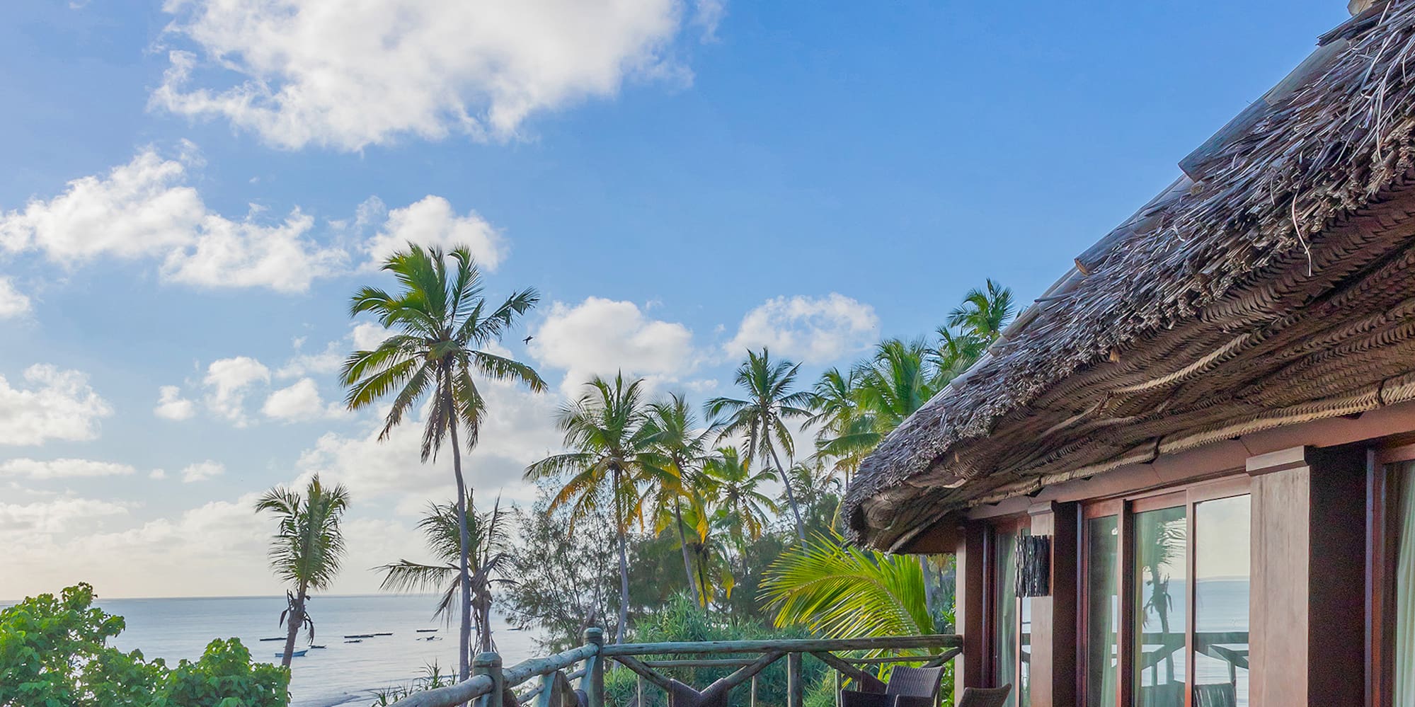 a deck with a thatched roof and a view of the ocean
