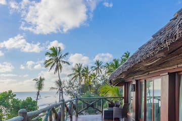 a deck with a thatched roof and a view of the ocean