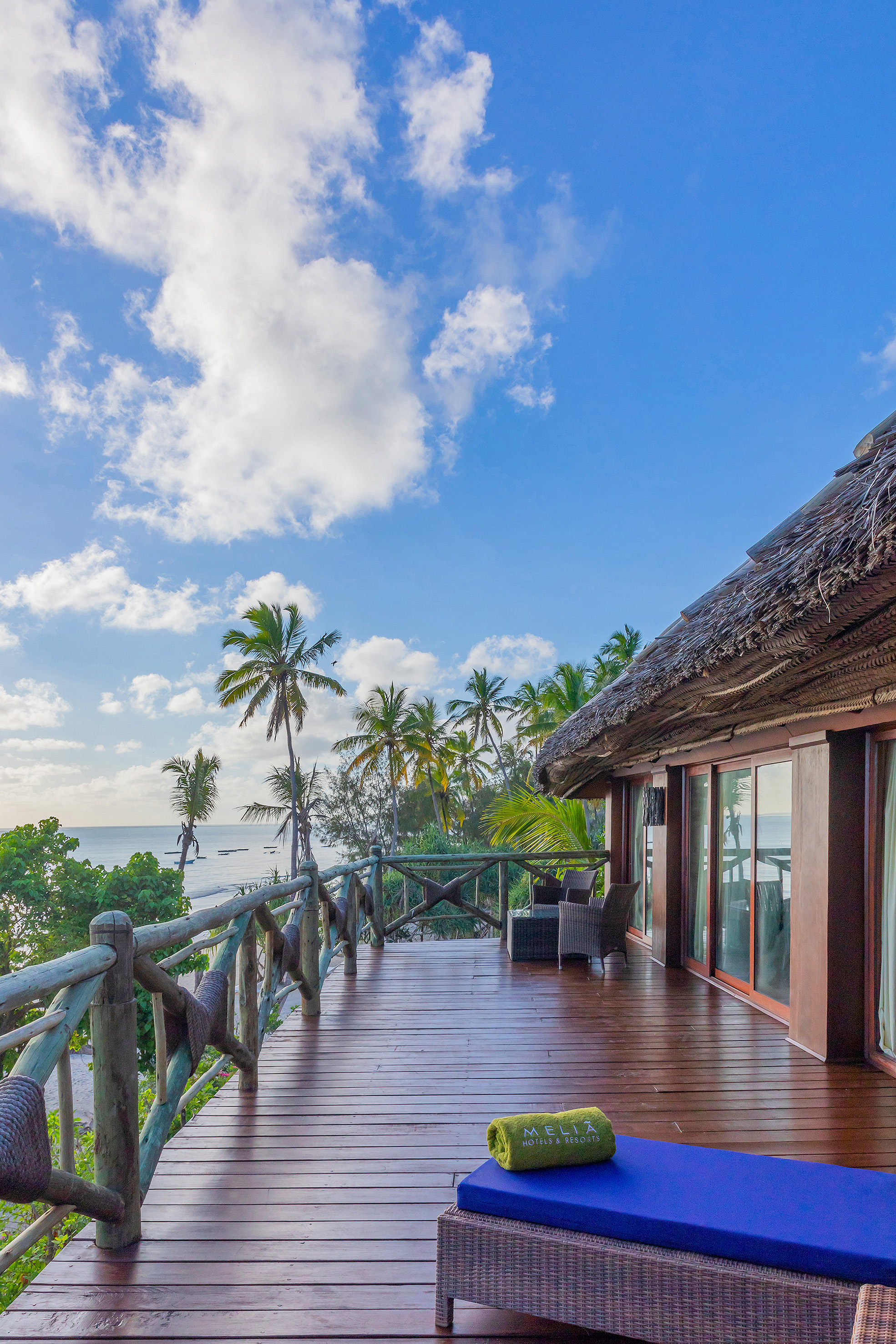 Oceanfront Melia resort balcony, wooden deck, tropical palm trees.