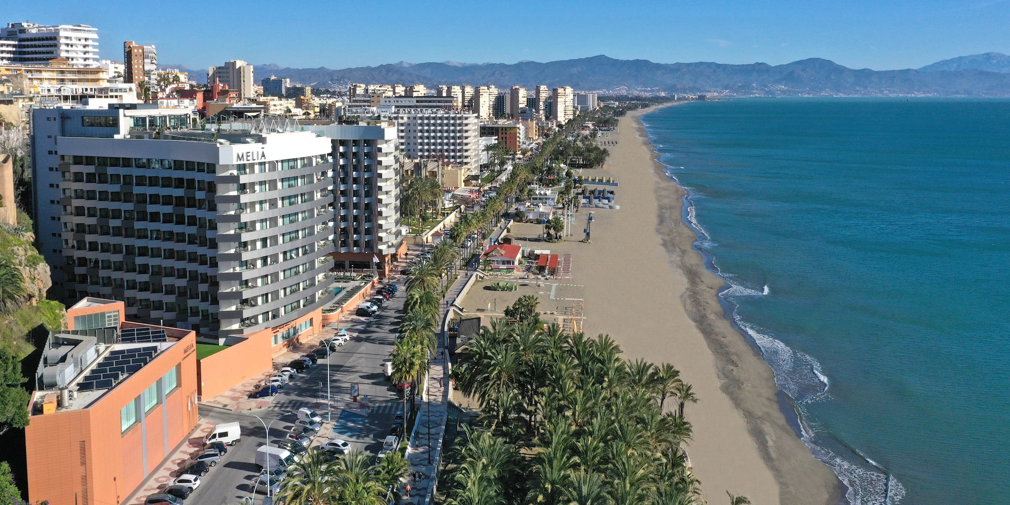a beach with buildings and palm trees
