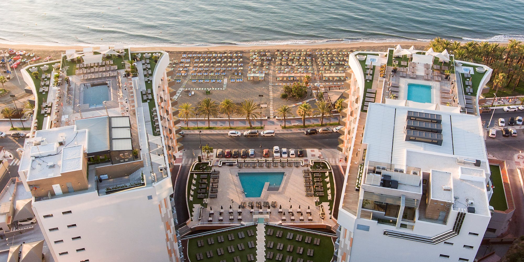 a aerial view of a resort with a beach and a lot of cars