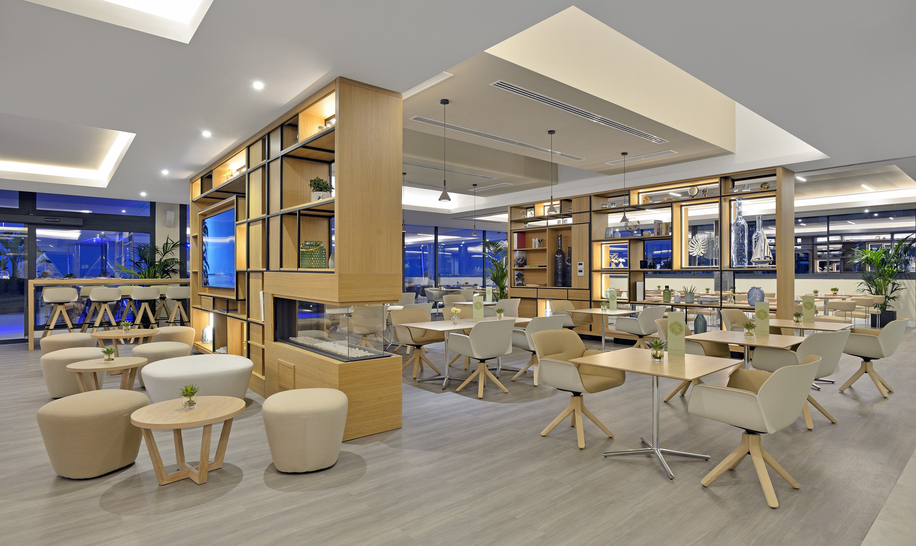 Modern restaurant lounge with wooden shelving, dining tables, and cozy seating.