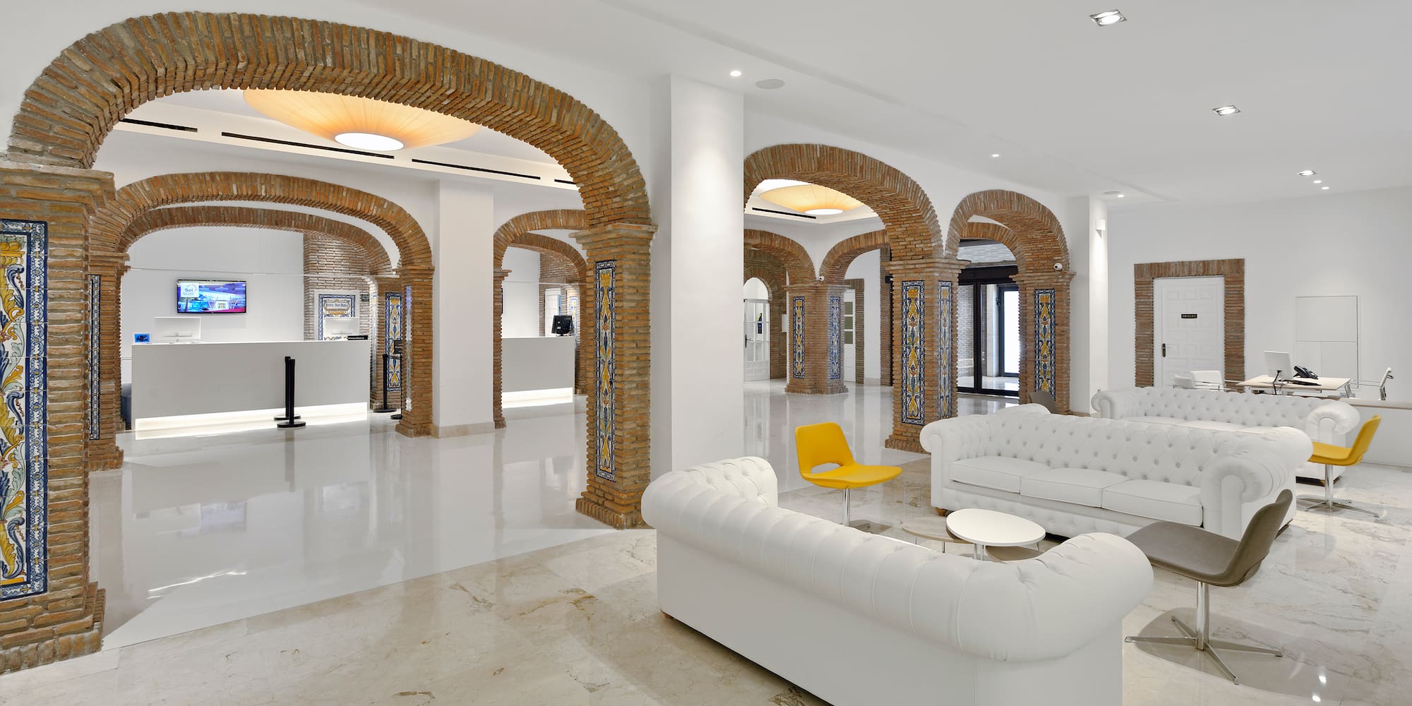 a white couches and a yellow chair in a room with columns