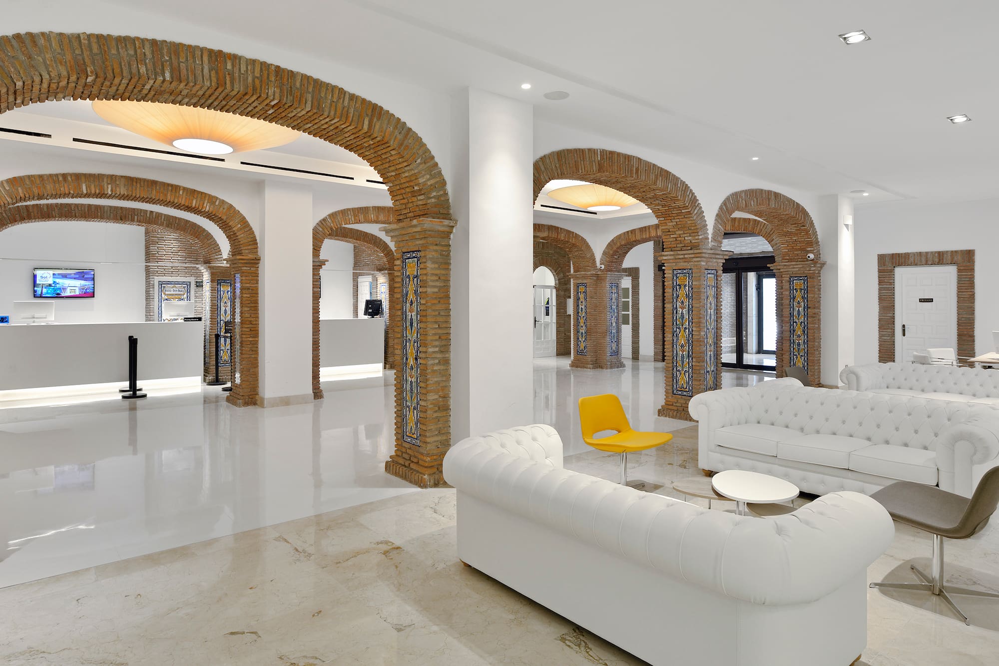 a white couches and a yellow chair in a room with columns