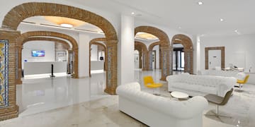 a white couches and a yellow chair in a room with columns
