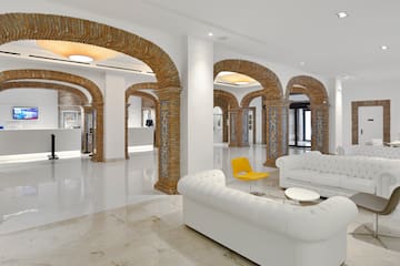 a white couches and a yellow chair in a room with columns