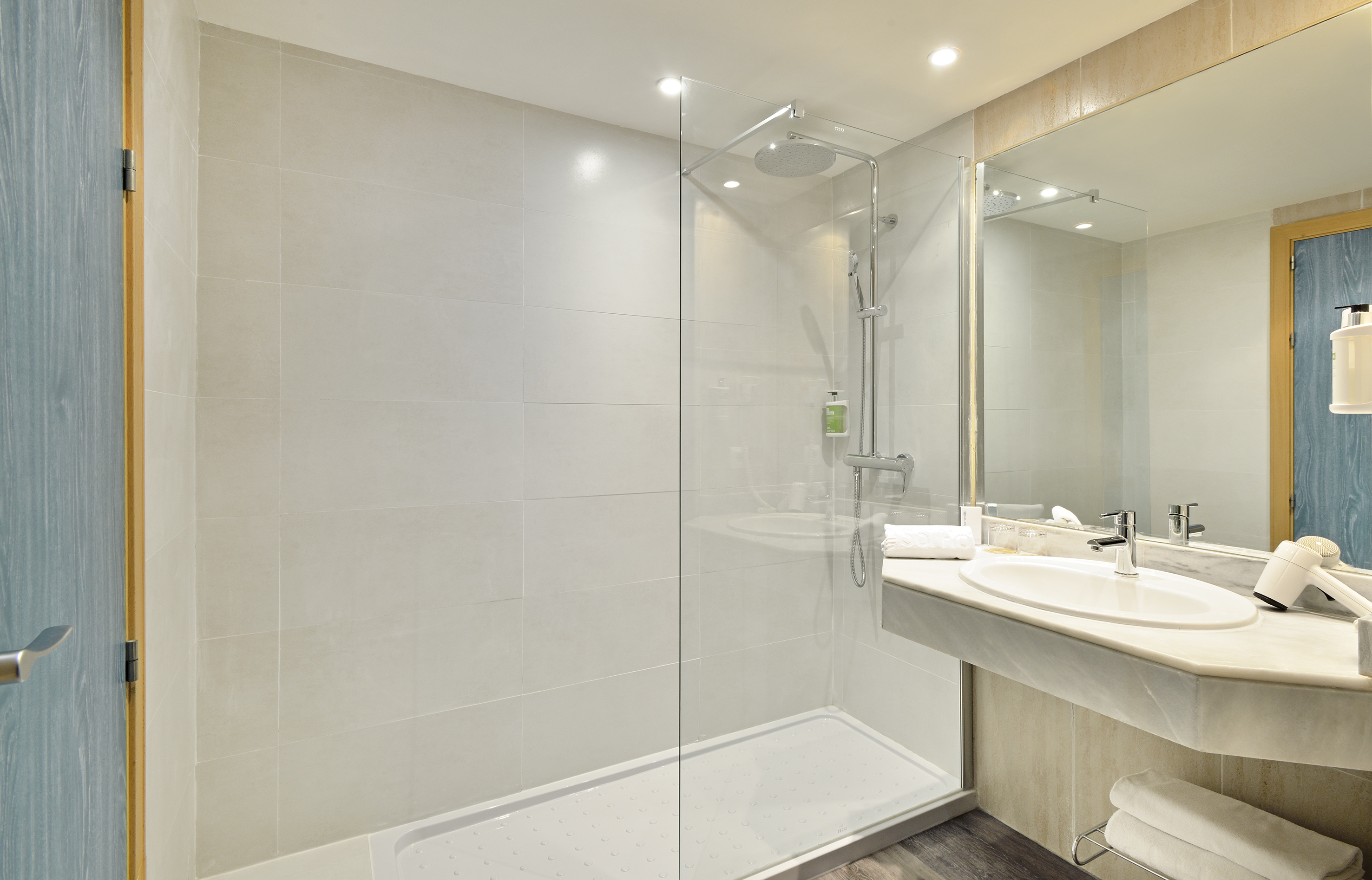 Modern hotel bathroom with walk-in shower, vanity, sink, and mirror.