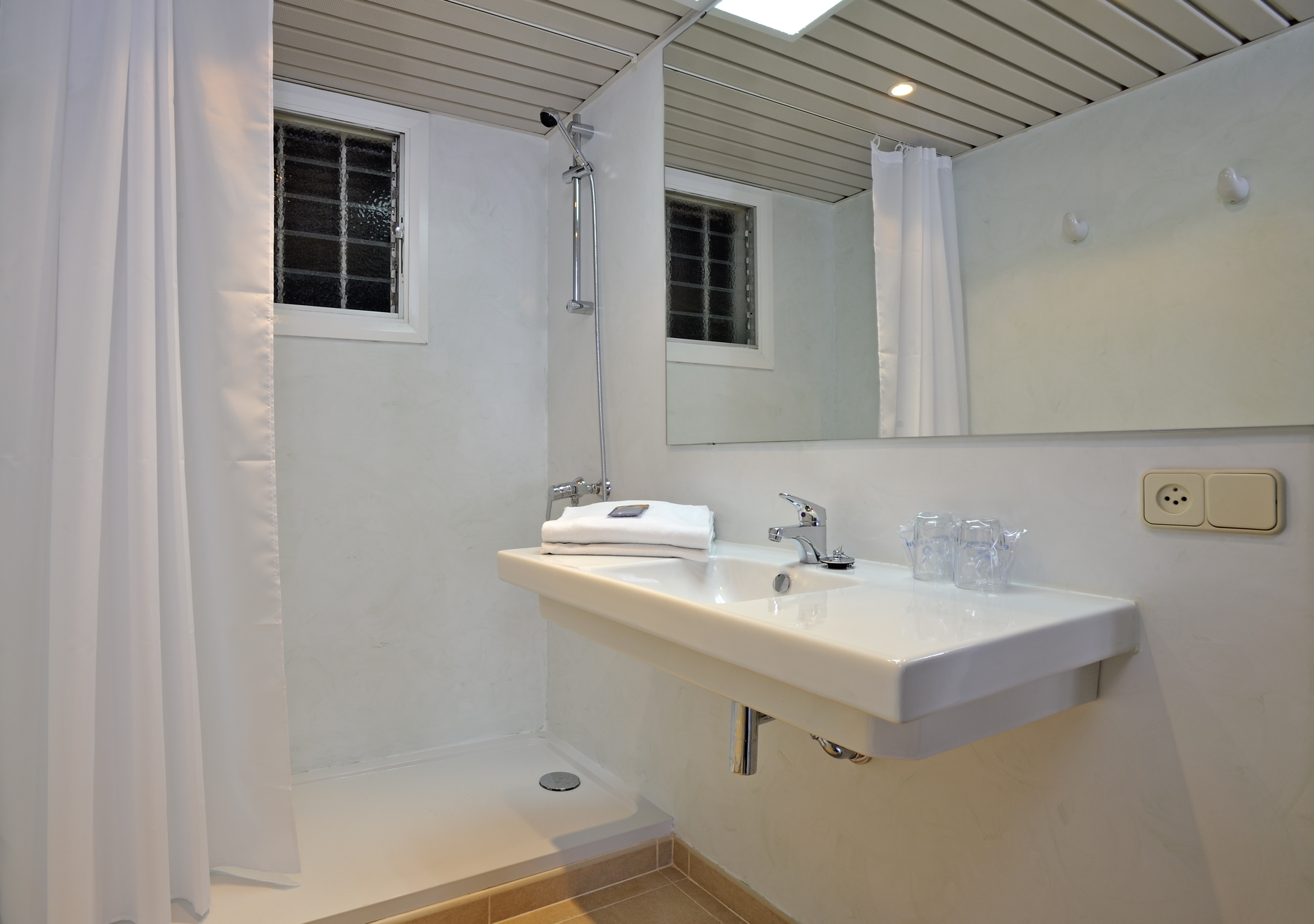 Bright, clean bathroom with shower, vanity sink, large mirror, and frosted window.