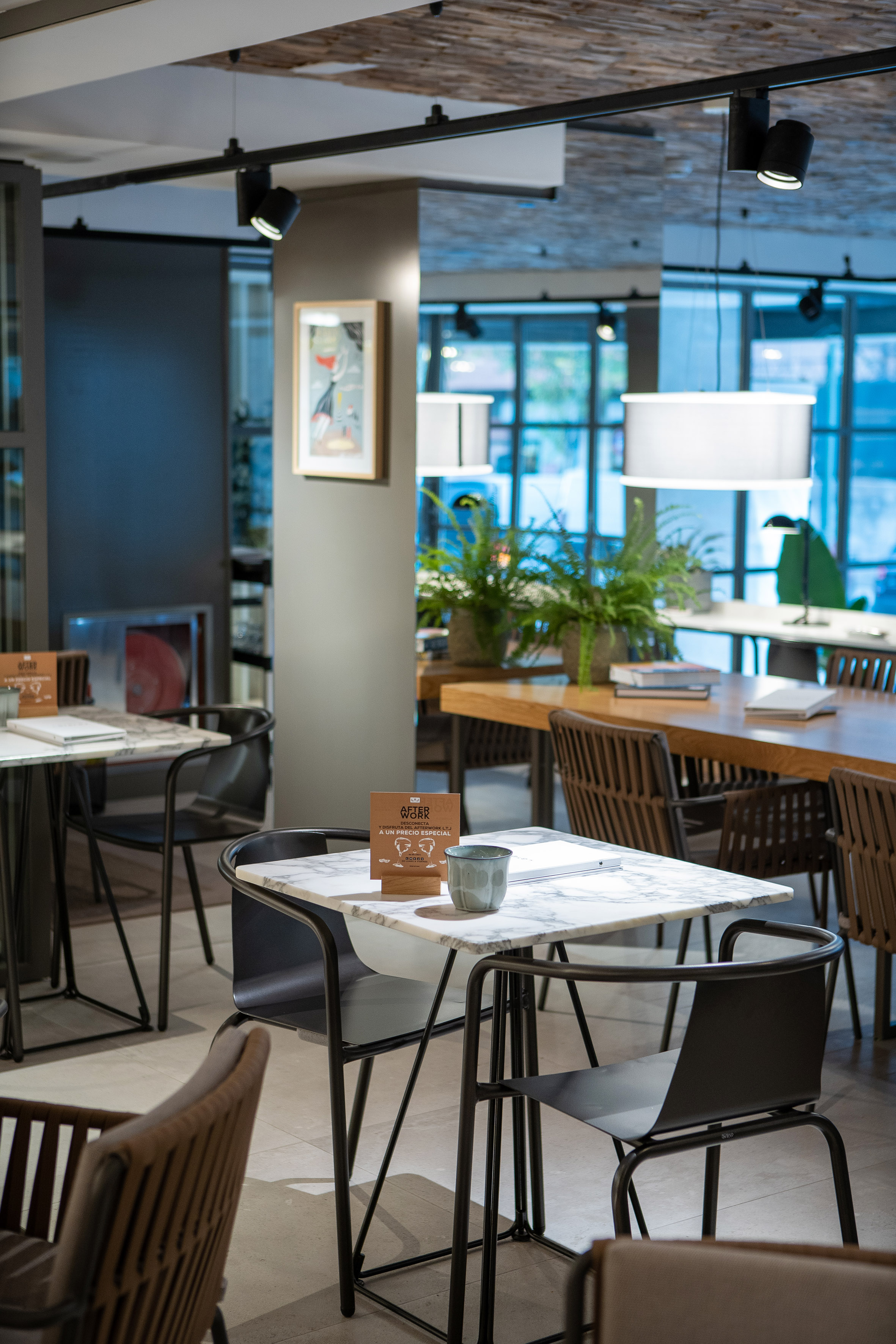 Modern cafe interior with marble tables, dark seating, and contemporary lighting.