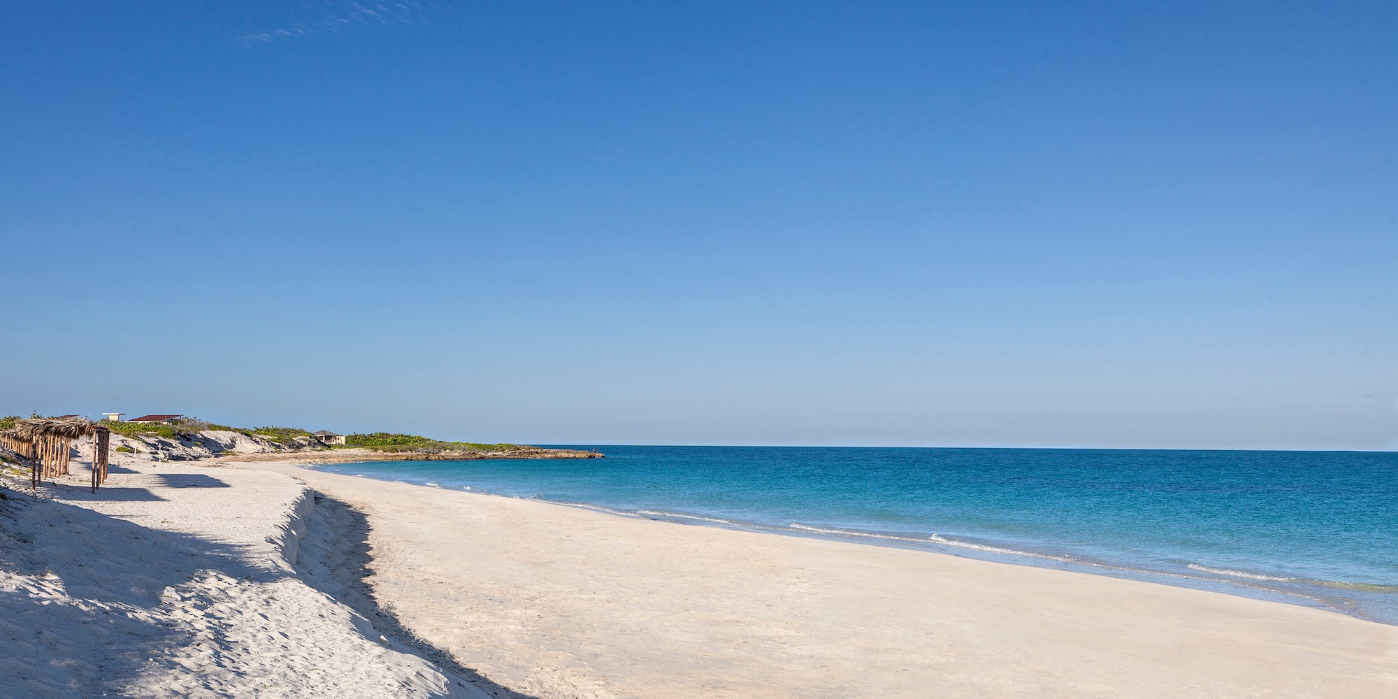 a sandy beach with blue water and a blue sky