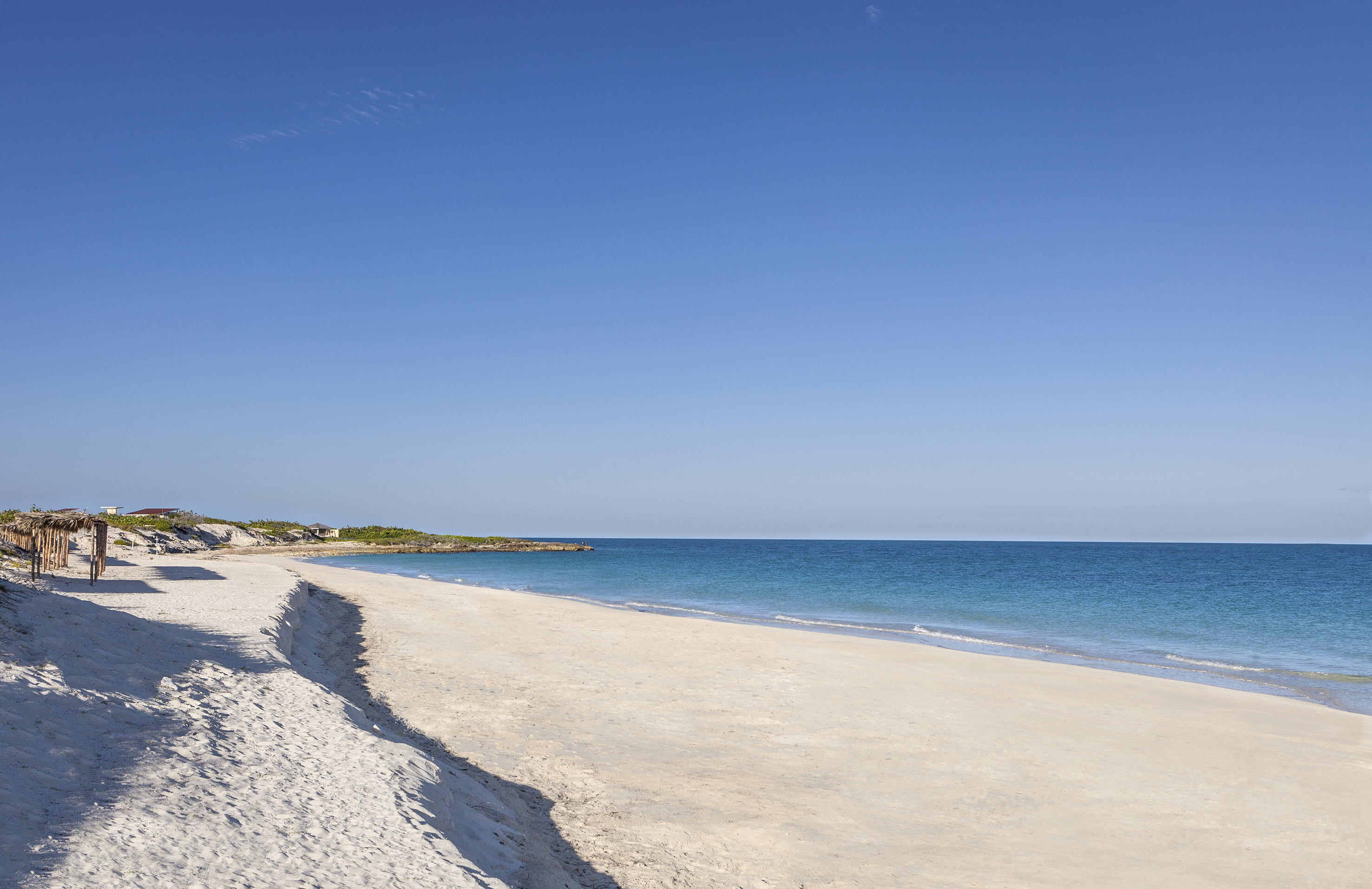 a sandy beach with blue water and a blue sky