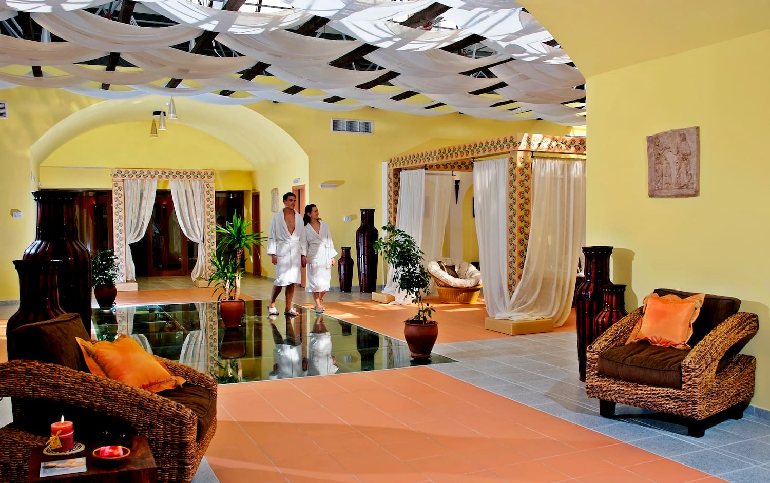 a couple in white robes in a room with a couch and plants