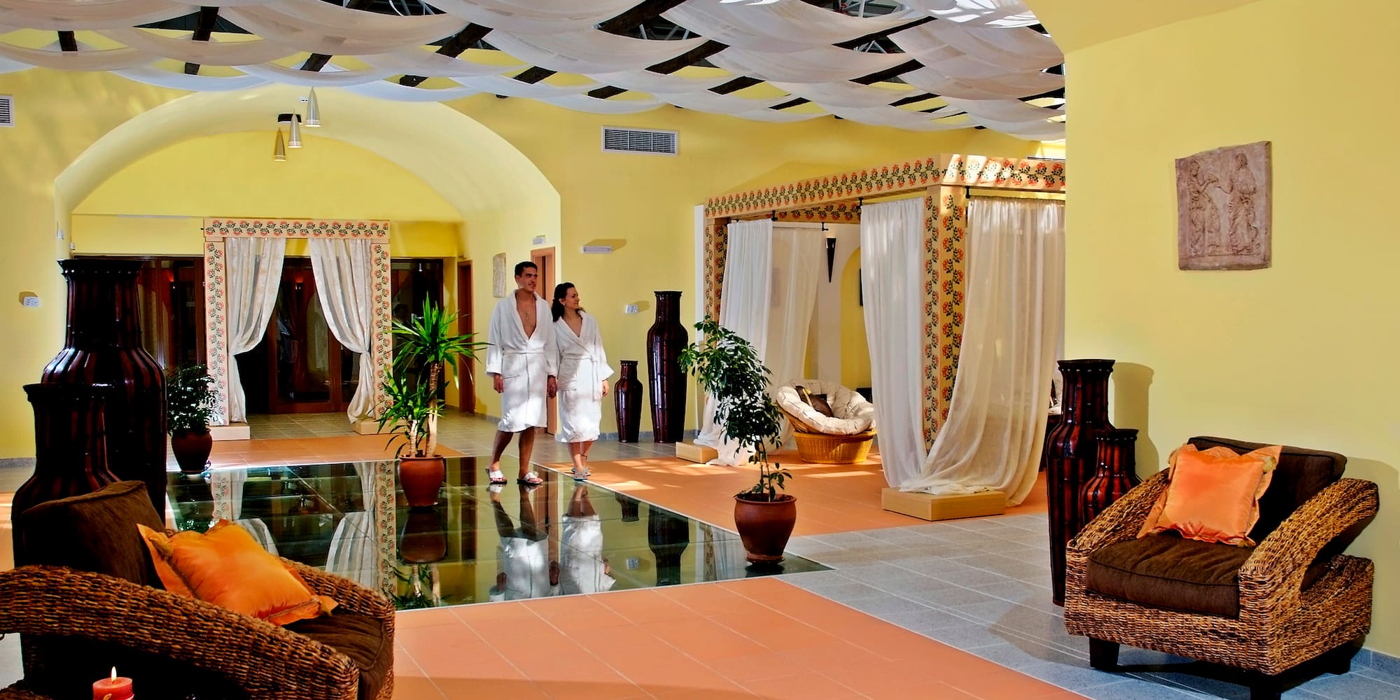 a couple in white robes in a room with a couch and plants