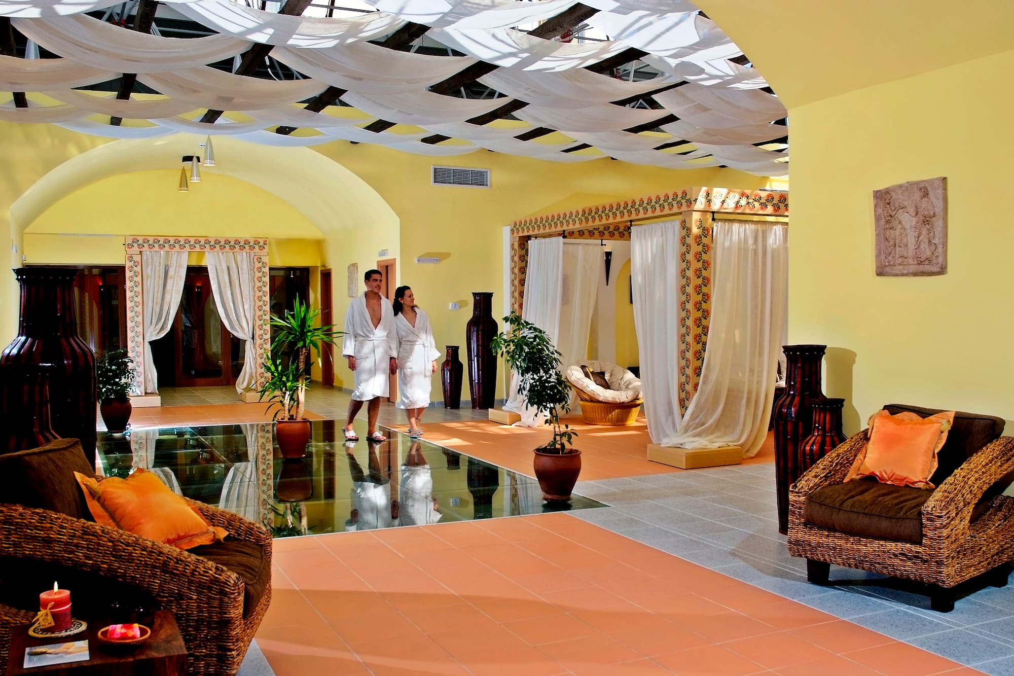 a couple in white robes in a room with a couch and plants