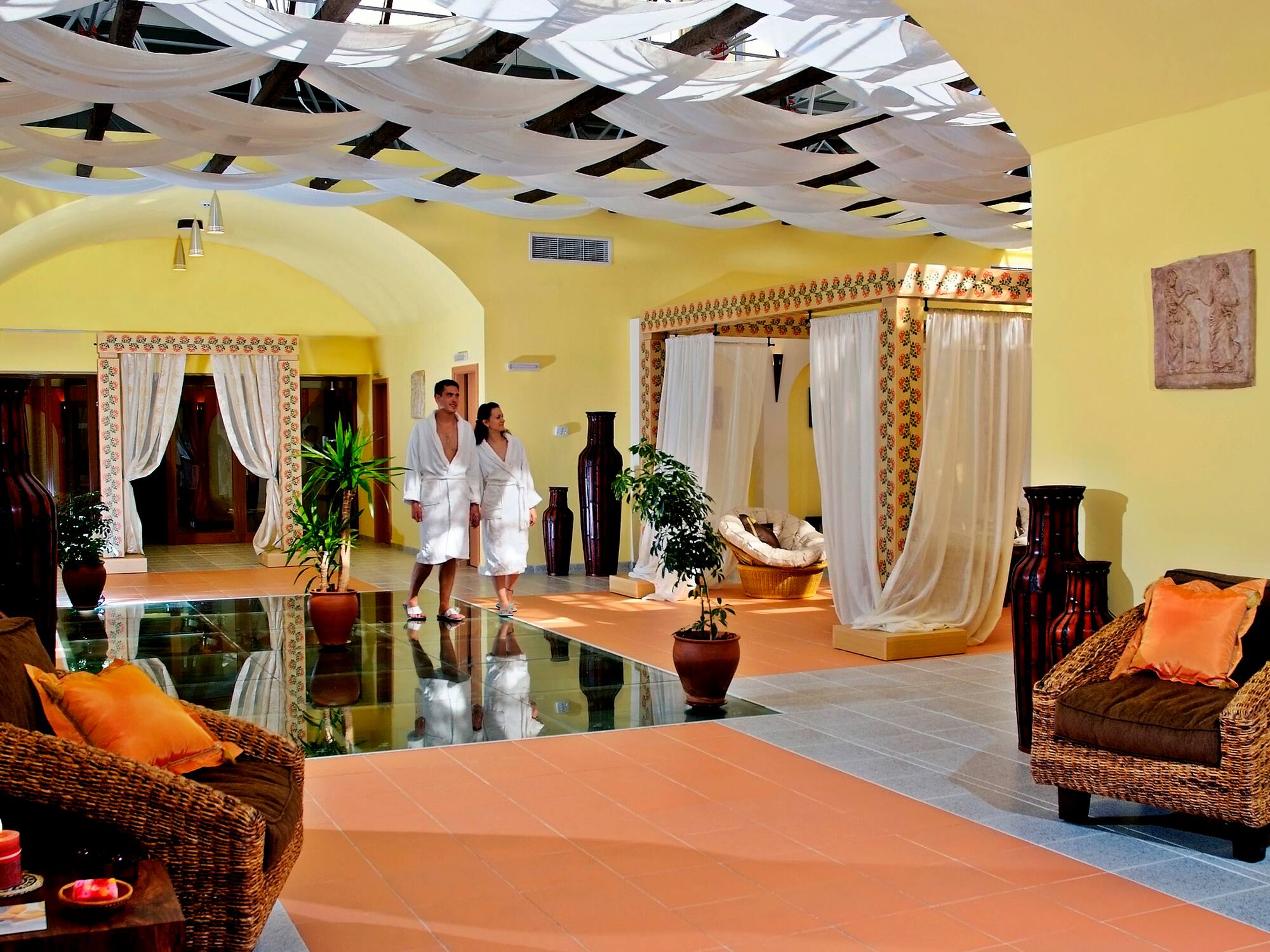 a couple in white robes in a room with a couch and plants