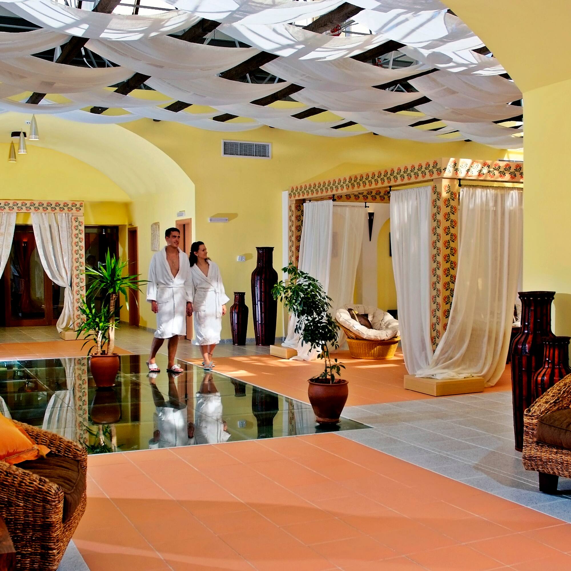 a couple in white robes in a room with a couch and plants