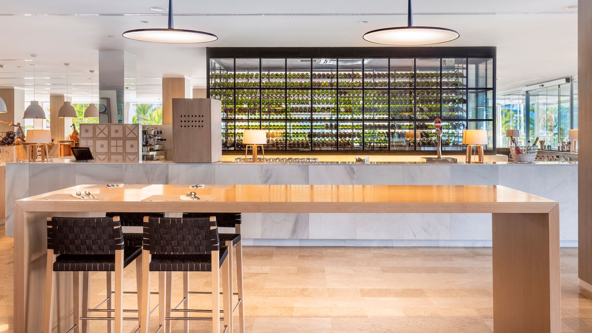 a long table with chairs in front of a wine rack
