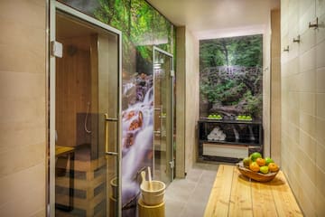 a room with a glass shower and a wooden bench