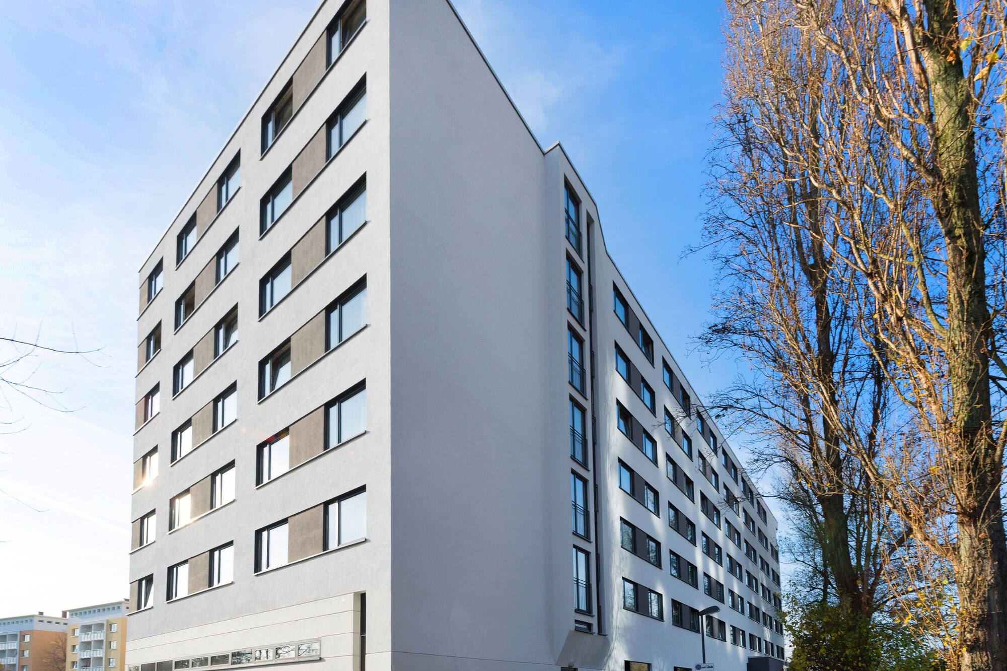 Modern architecture: white multi-story building, many windows, bare trees.