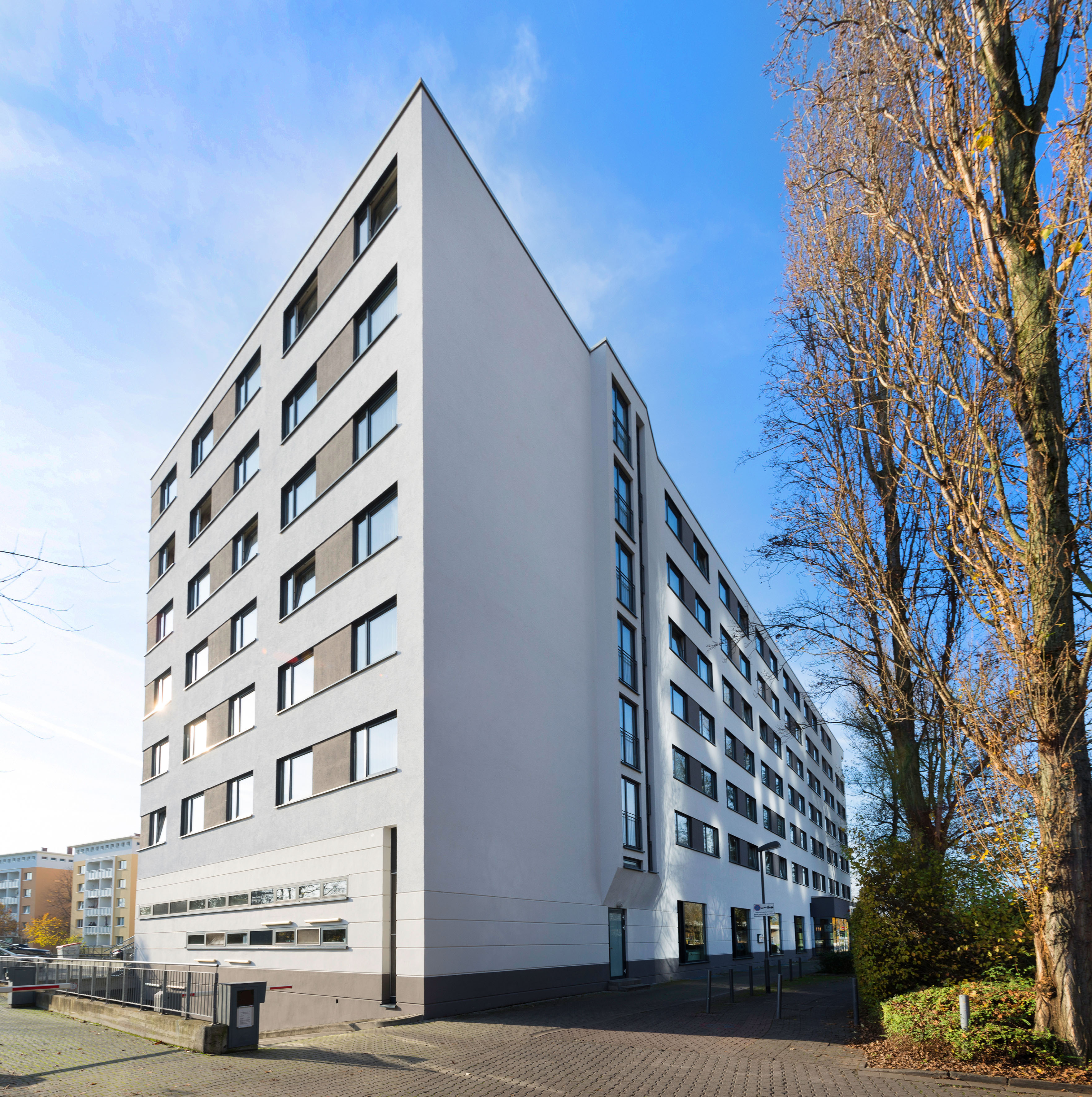 Modern architecture: white multi-story building, many windows, bare trees.