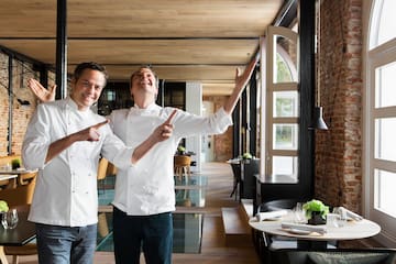 two men wearing white chef jackets pointing at something