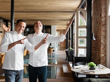 two men wearing white chef jackets pointing at something