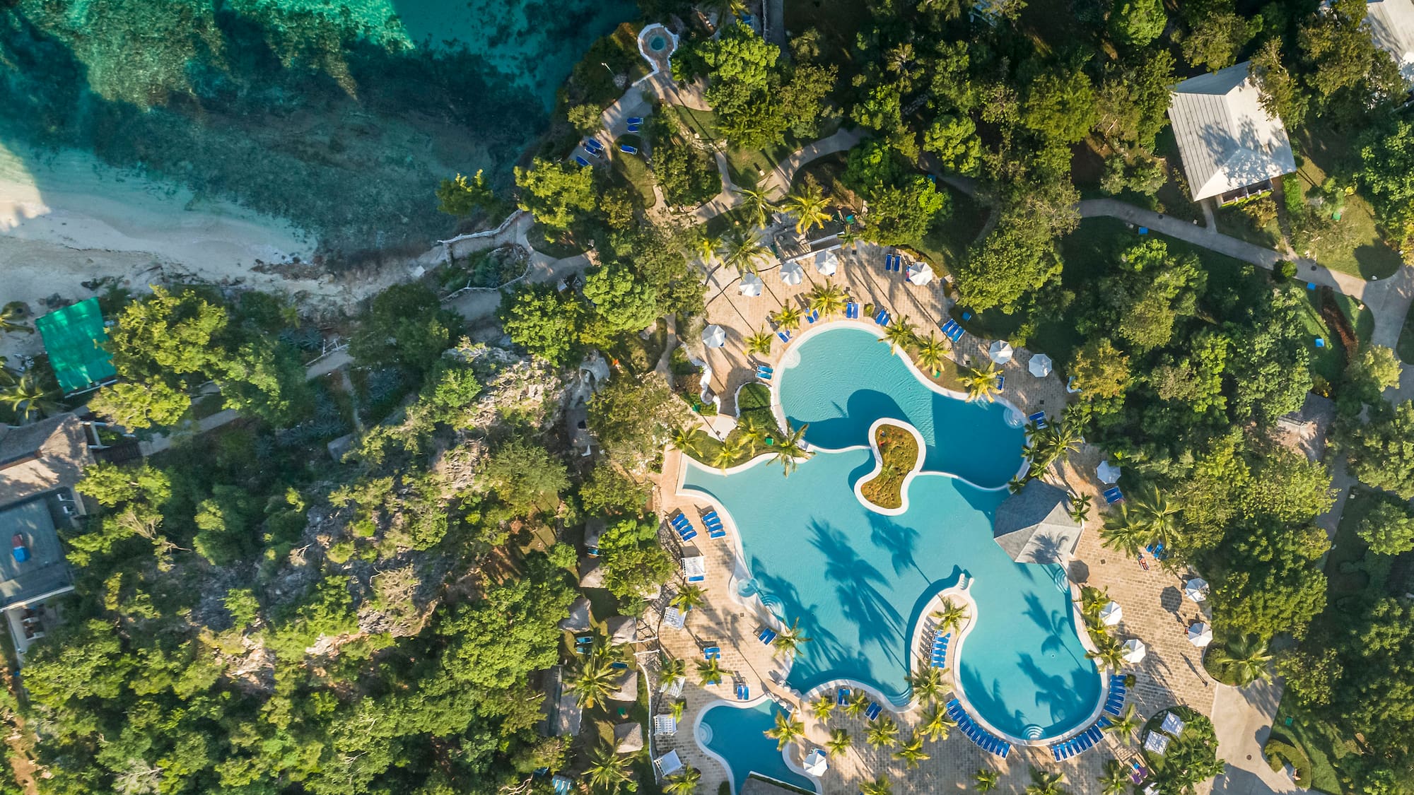 an aerial view of a resort with a pool and trees