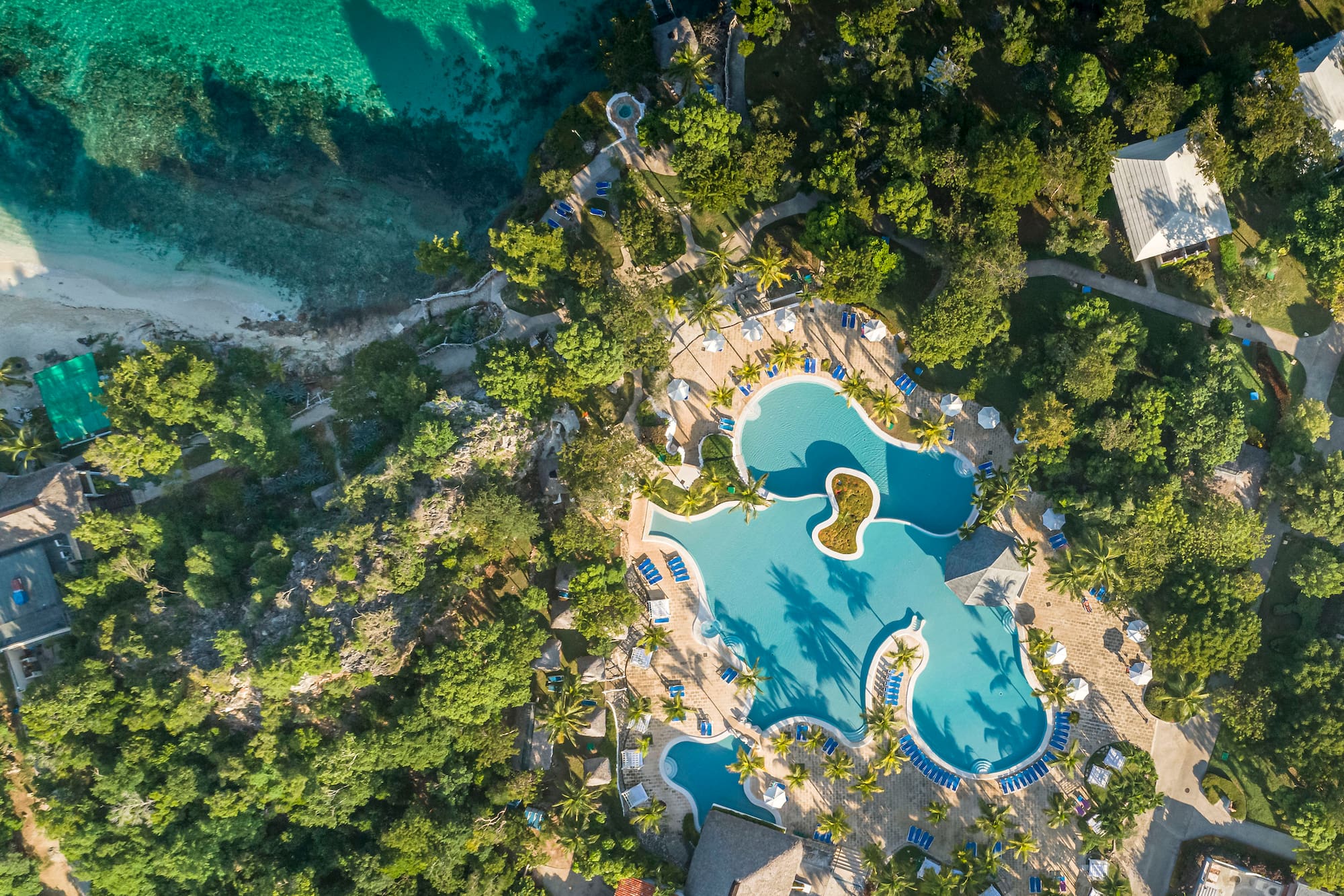an aerial view of a resort with a pool and trees